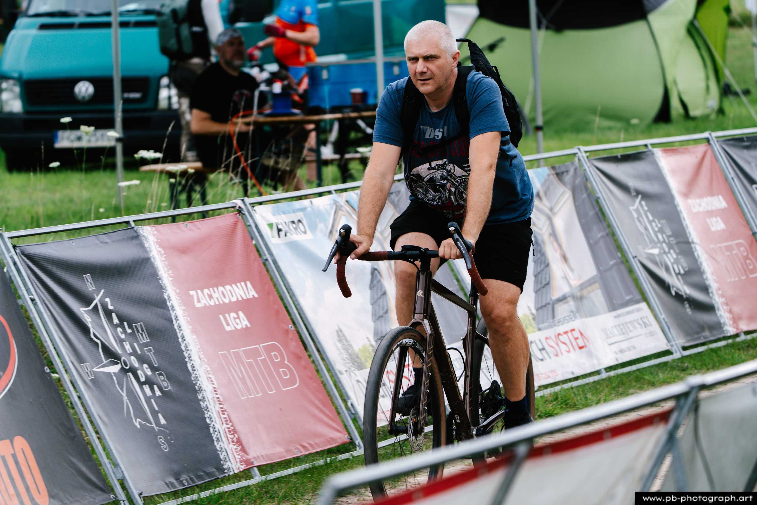 Zawodnik na rowerze podczas wyścigów MTB w Szczecinie, zbliżenie na trasę z bannerami reklamowymi.