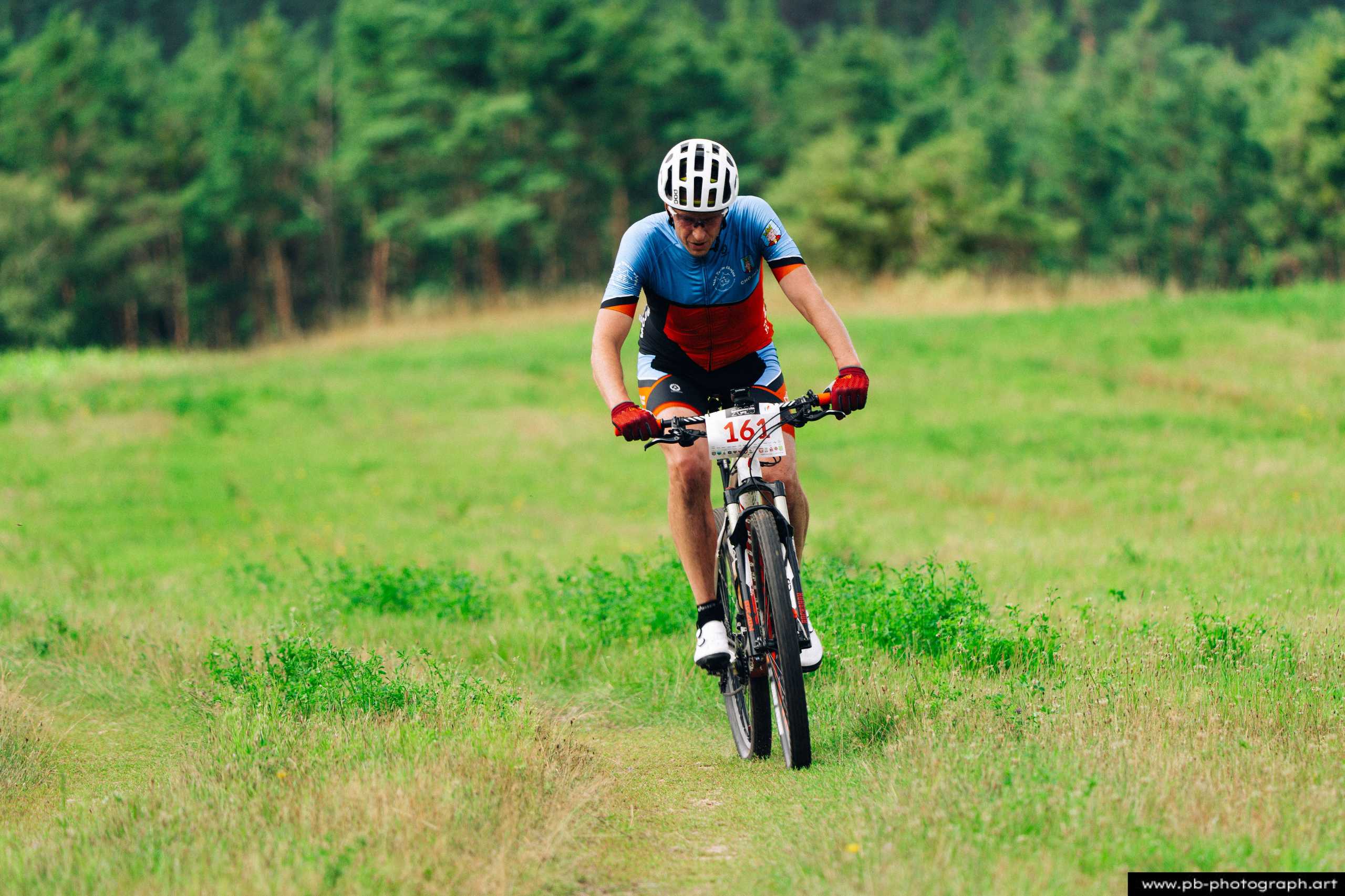 Zawodnik na rowerze górskim podczas wyścigu MTB w Szczecinie, pokonujący zieloną trasę w lesie.