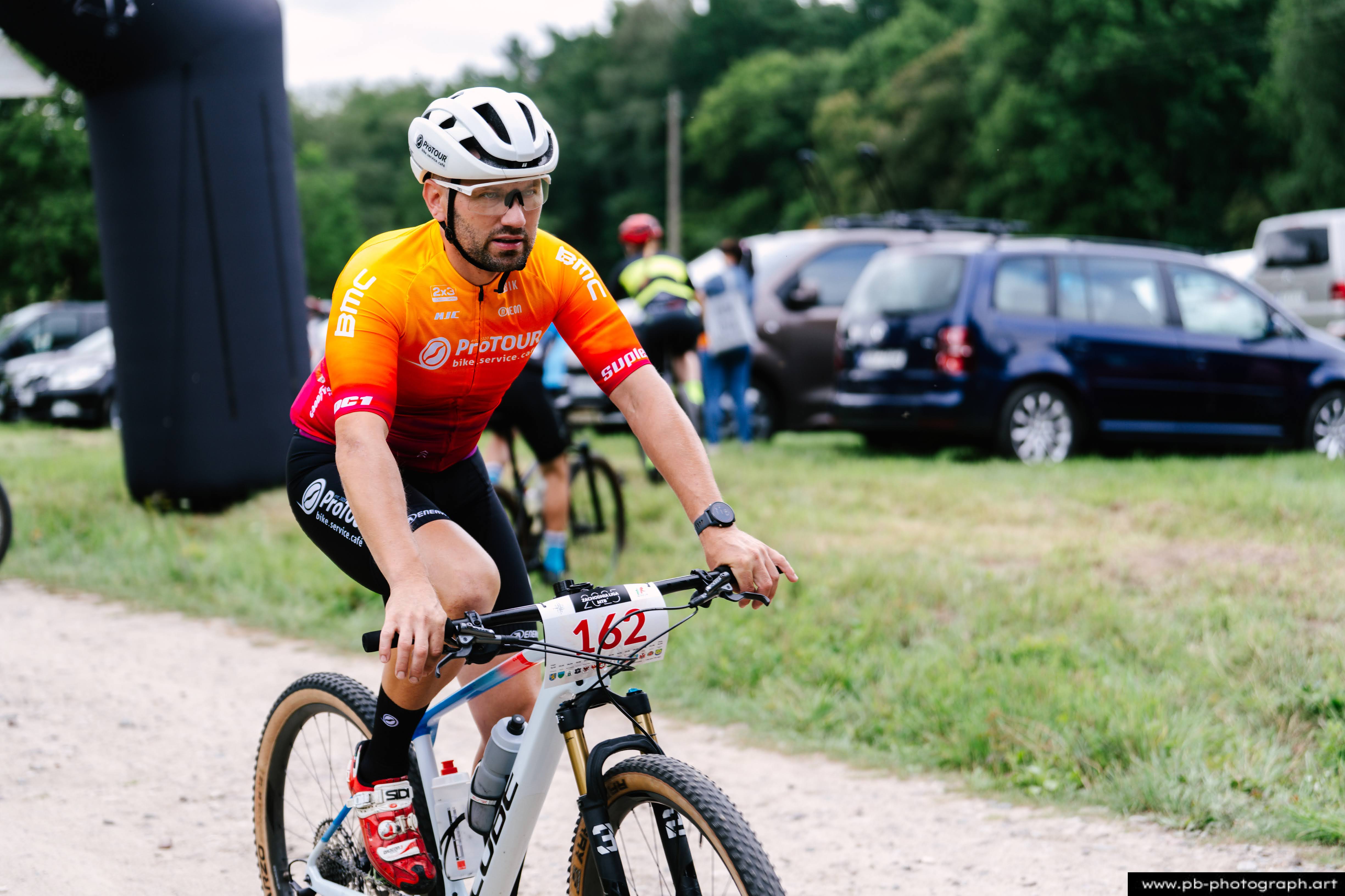 Fotografia z drona podczas Rajdu MTD — zawodnik MTB na trasie wyścigu w Szczecinie, w tle samochody i zieleń.