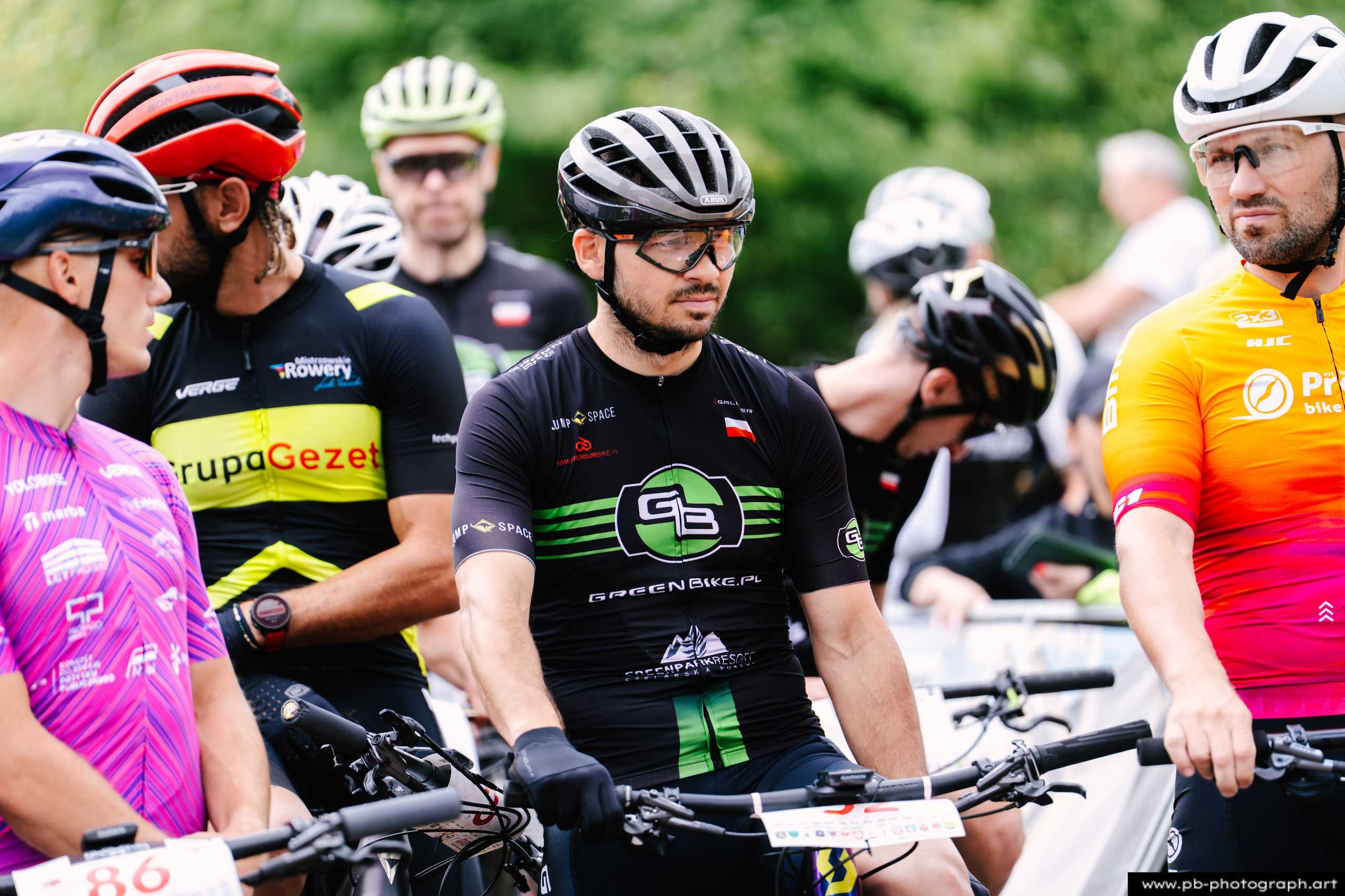 Zawodnicy MTB w oczekiwaniu na start wyścigu, zbliżenie na uczestnika w zielonym stroju w Szczecinie.