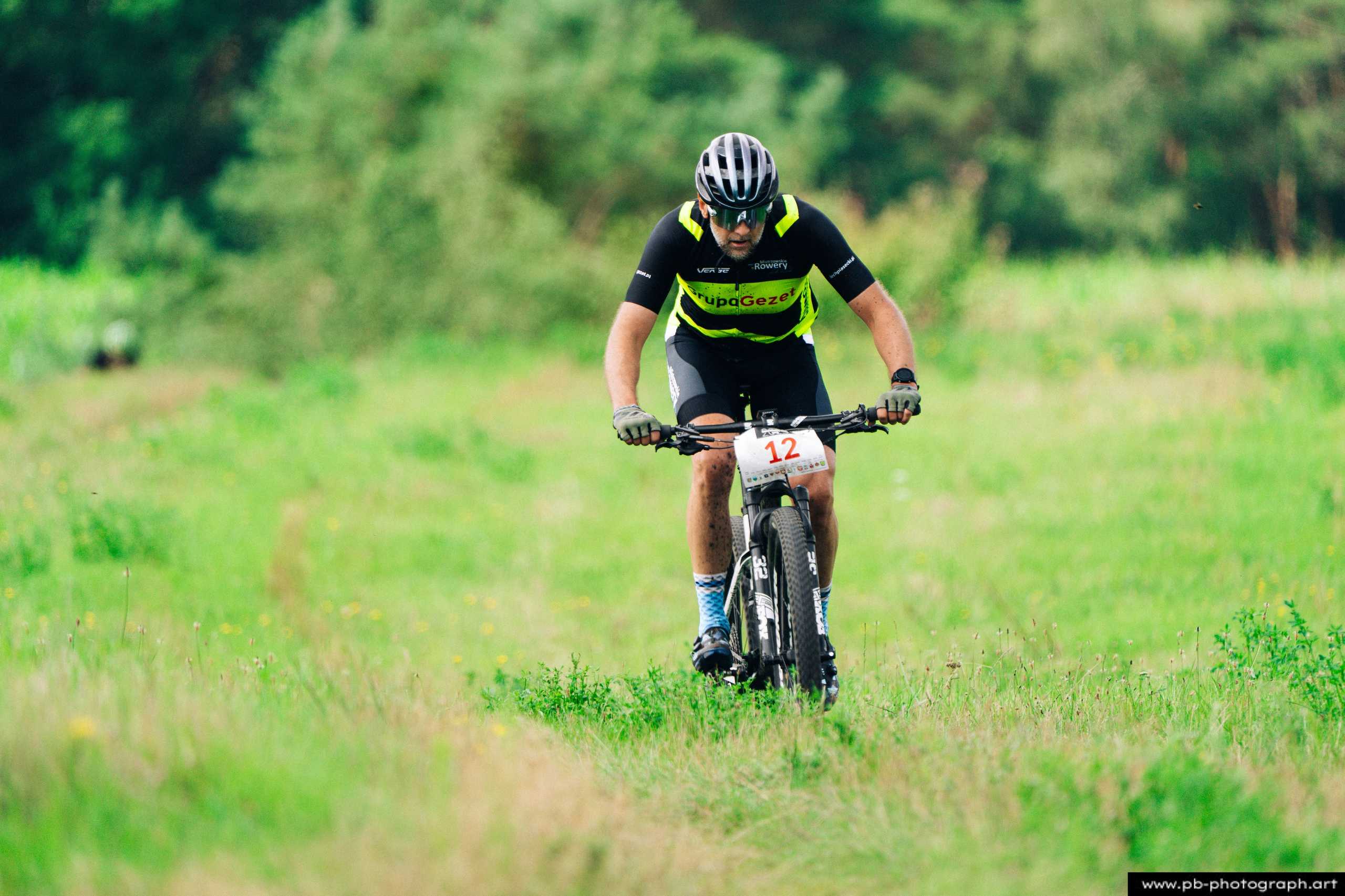 Zawodnik MTB pokonujący trasę wyścigu w Szczecinie, ujęcie z bliska ukazujące zmagania na zielonym terenie.