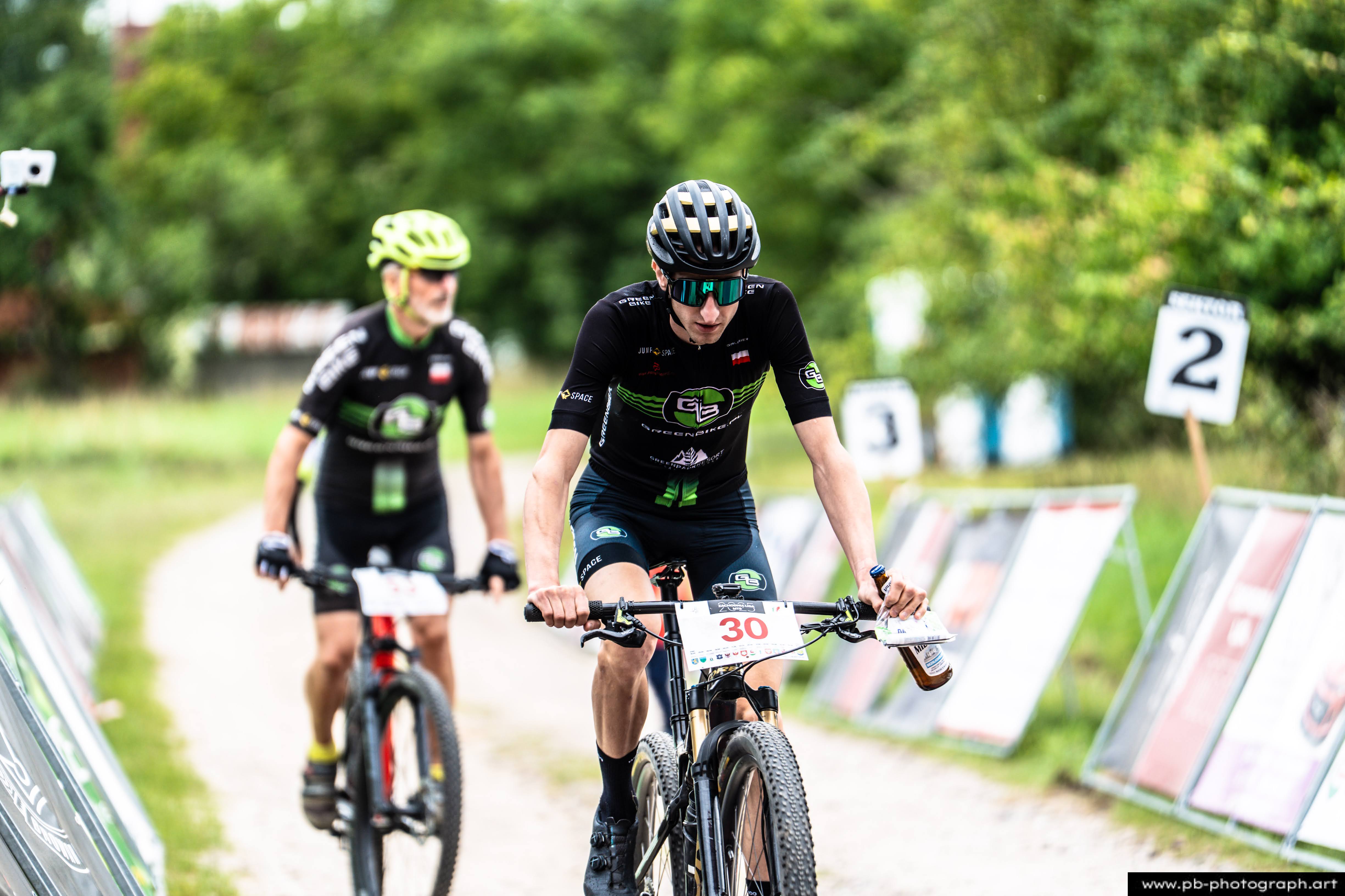 Zawodnik na rowerze górskim podczas wyścigu MTB w Szczecinie, zbliżenie na trasę i oznaczenia zawodów.