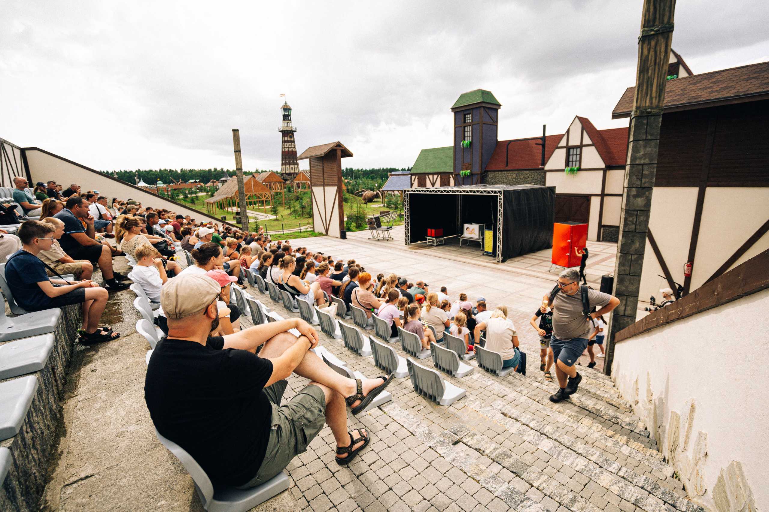 Widok na publiczność podczas pokazu iluzjonisty w Hossolandzie, z widoczną sceną i asystentką.