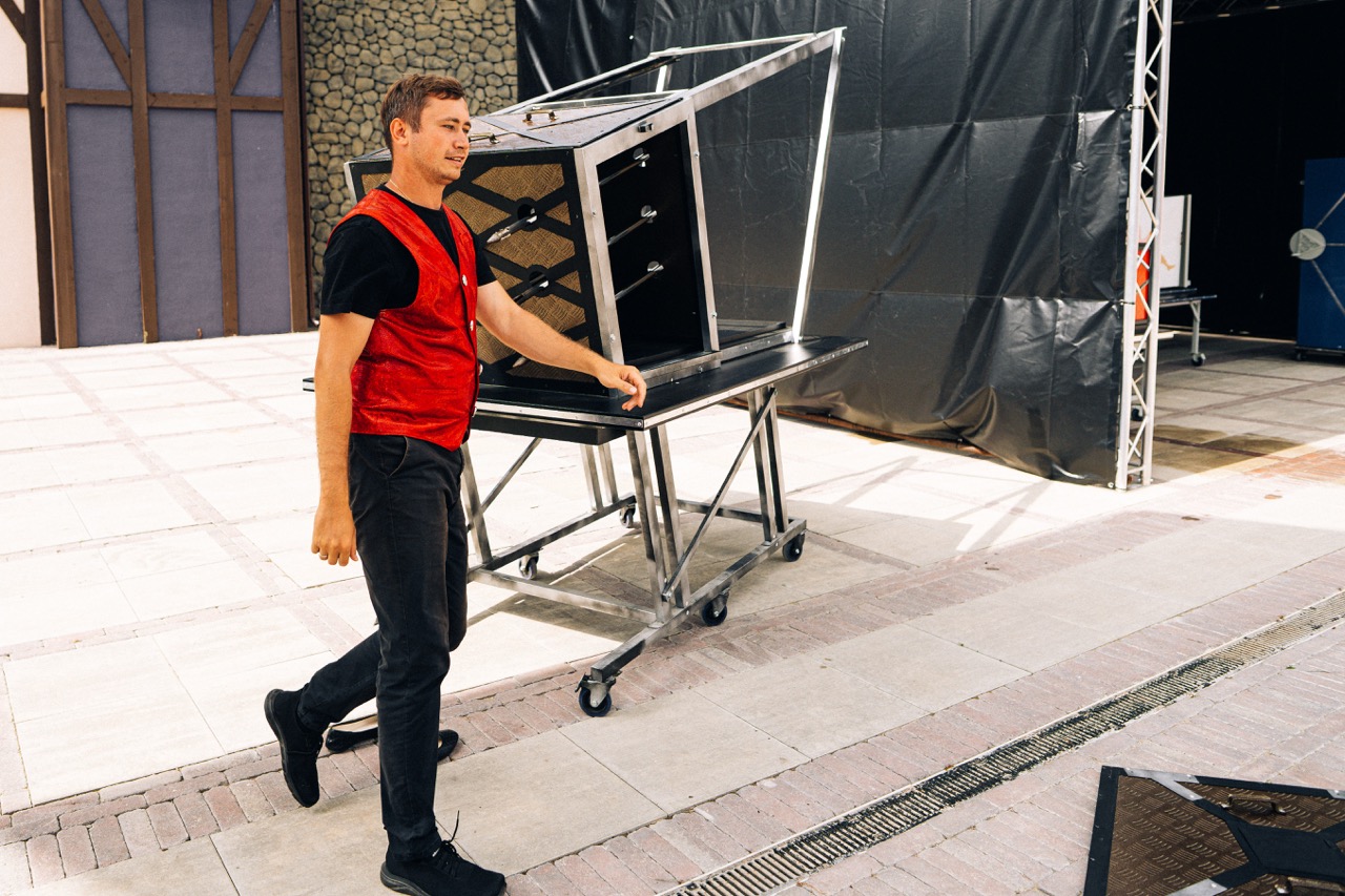Iluzjonista w czerwonej kamizelce przemieszcza się z rekwizytem na scenie w Szczecinie.