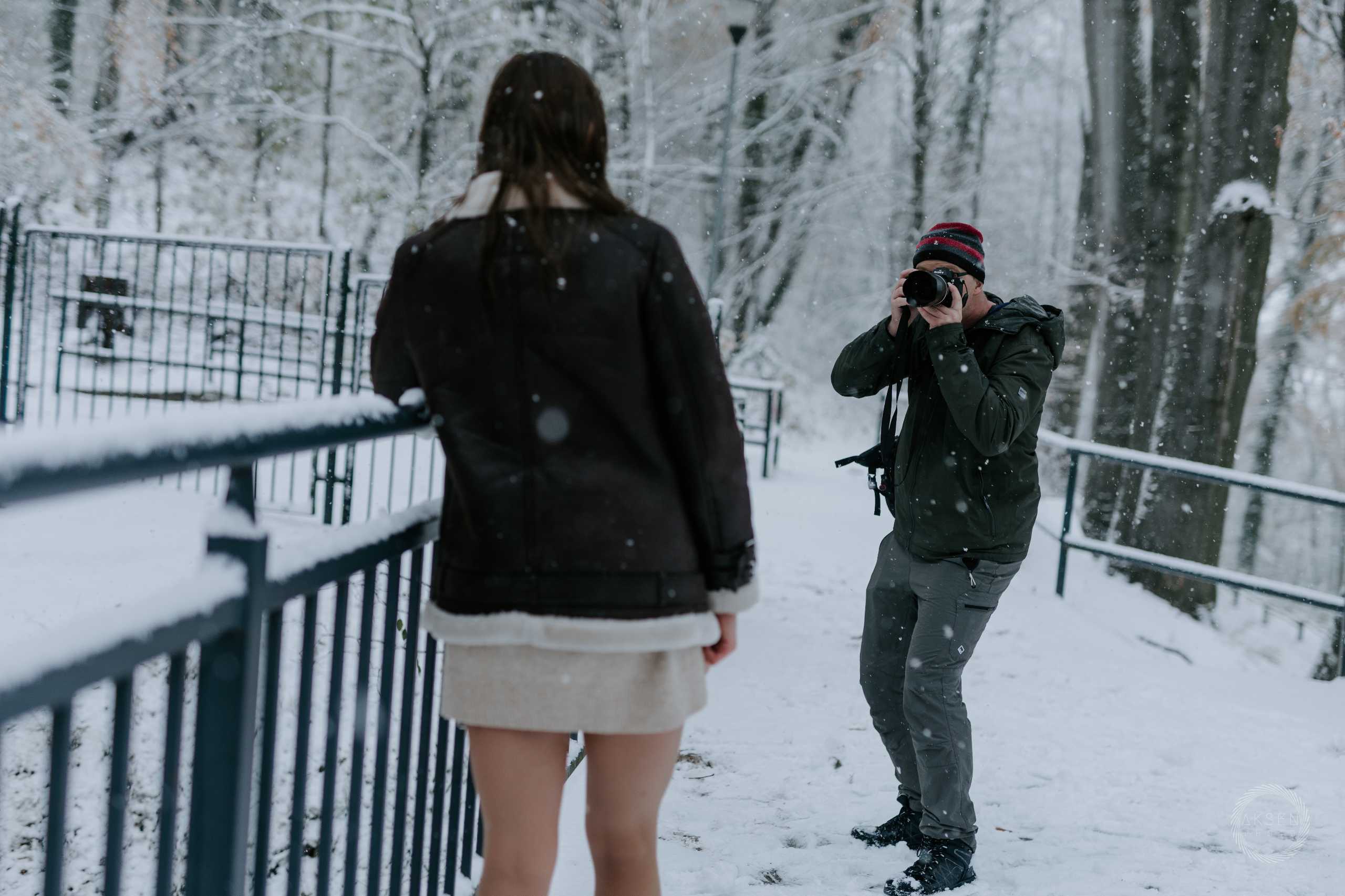 Fotografia wizerunkowa w zimowym plenerze w Szczecinie — fotograf uchwycony podczas sesji z modelką w śniegu.