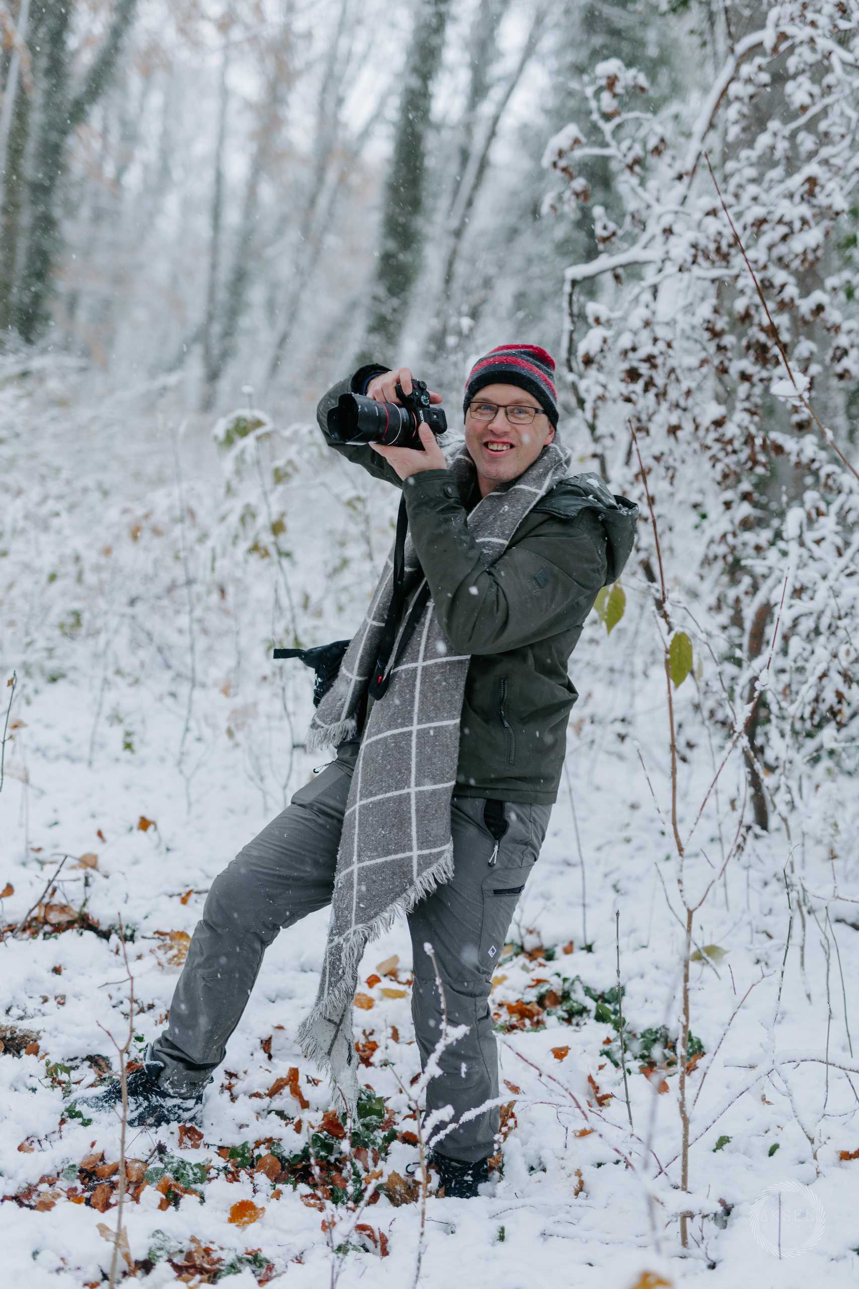 Fotografia wizerunkowa w Szczecinie — fotograf w zimowym plenerze, uchwycony podczas pracy w śniegu.