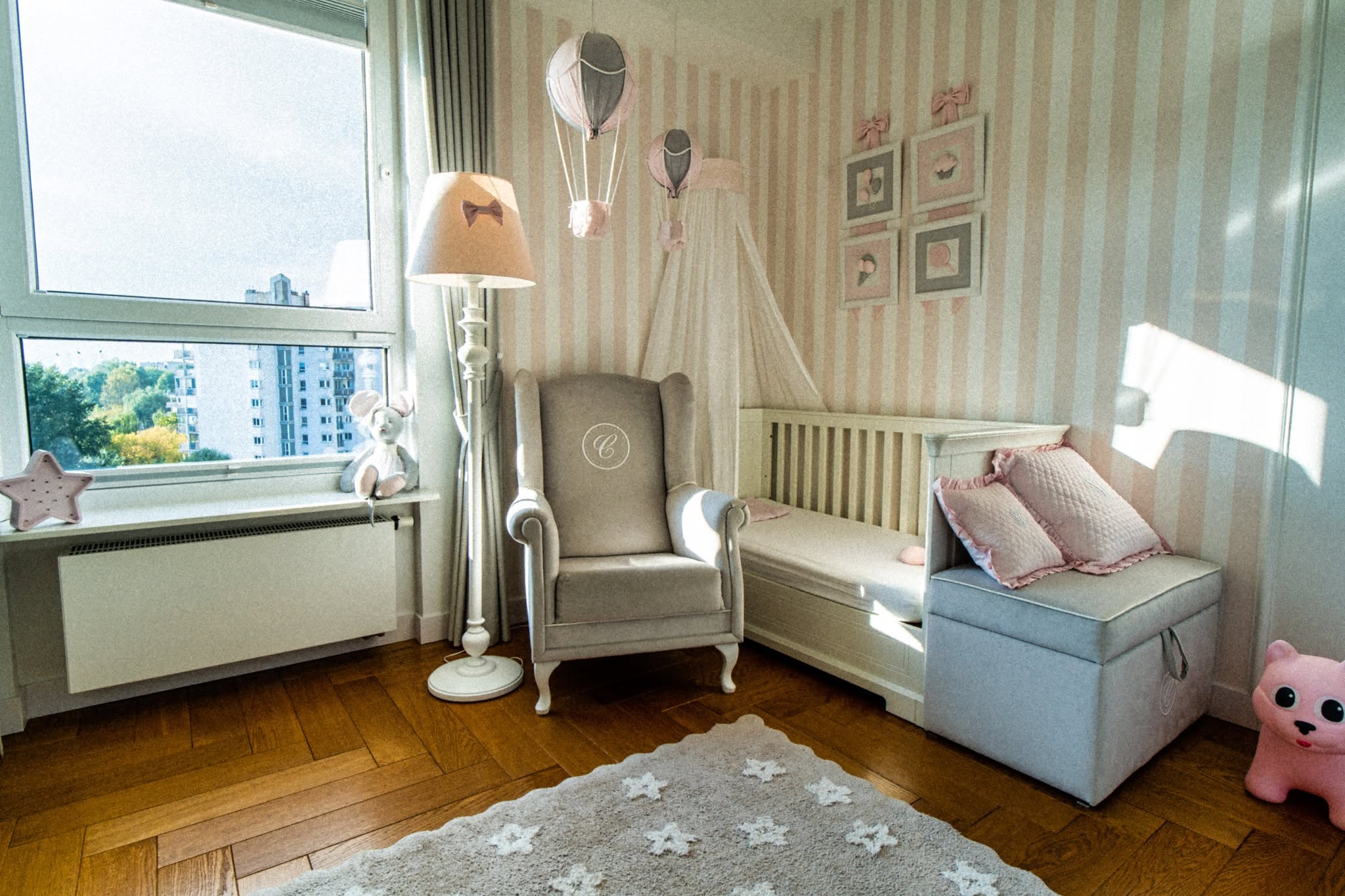 Stylowe wnętrze dziecięcego pokoju z pastelowymi akcentami oraz eleganckim fotelem w apartamencie w Warszawie.