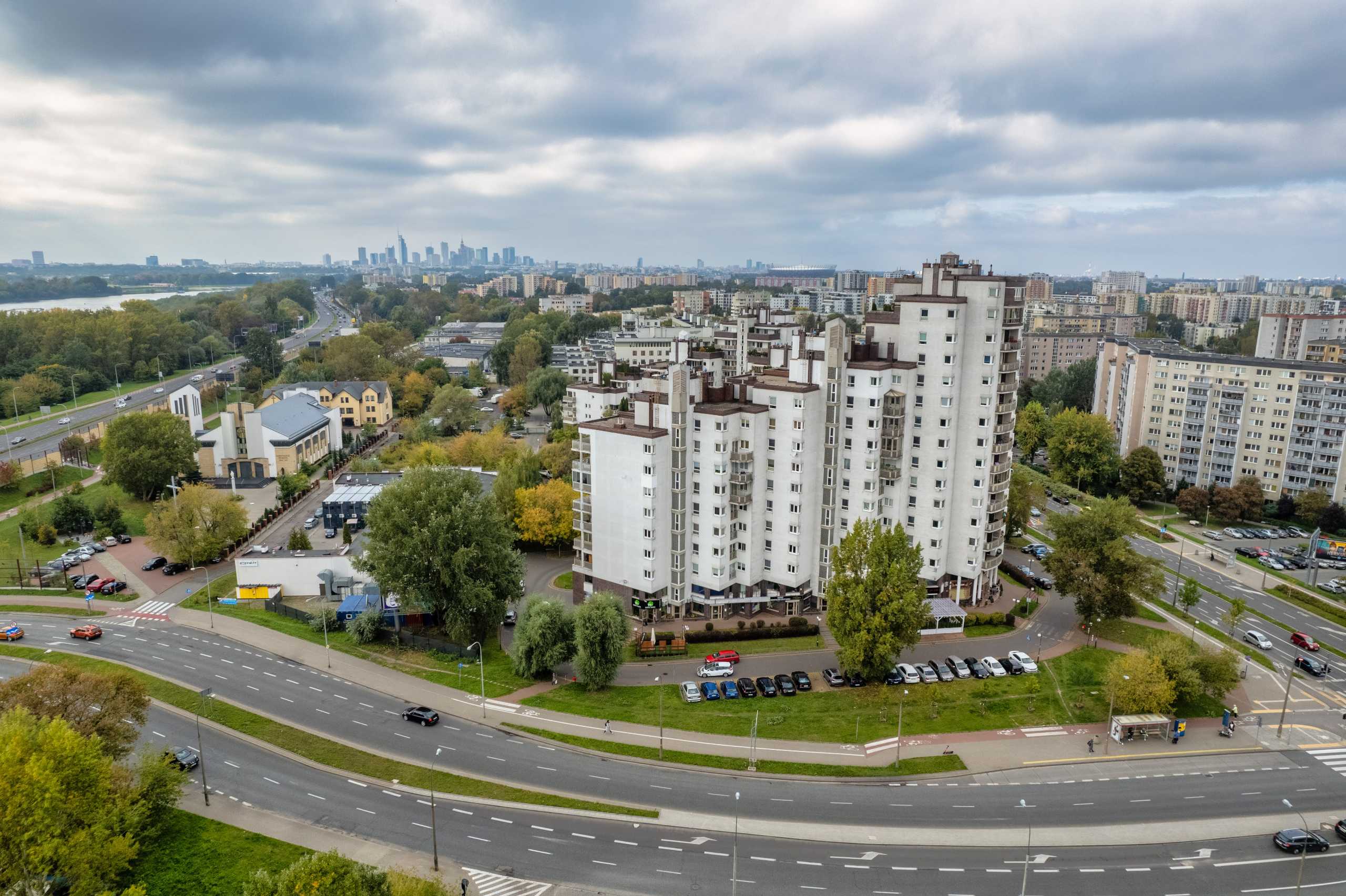 Fotografia z drona ukazująca okazały apartament w Warszawie oraz okoliczne tereny zielone i infrastrukturę drogową.