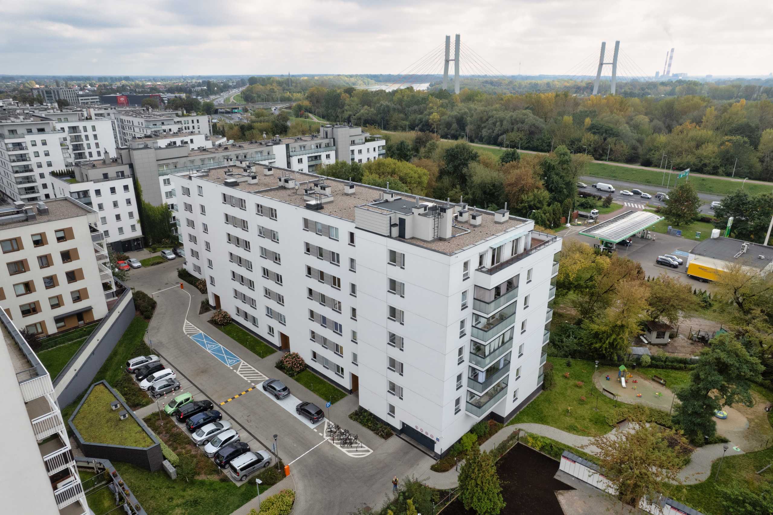 Fotografia wnętrz z drona, ukazująca nowoczesny apartamentowiec w Warszawie z widokiem na okoliczne tereny zielone.