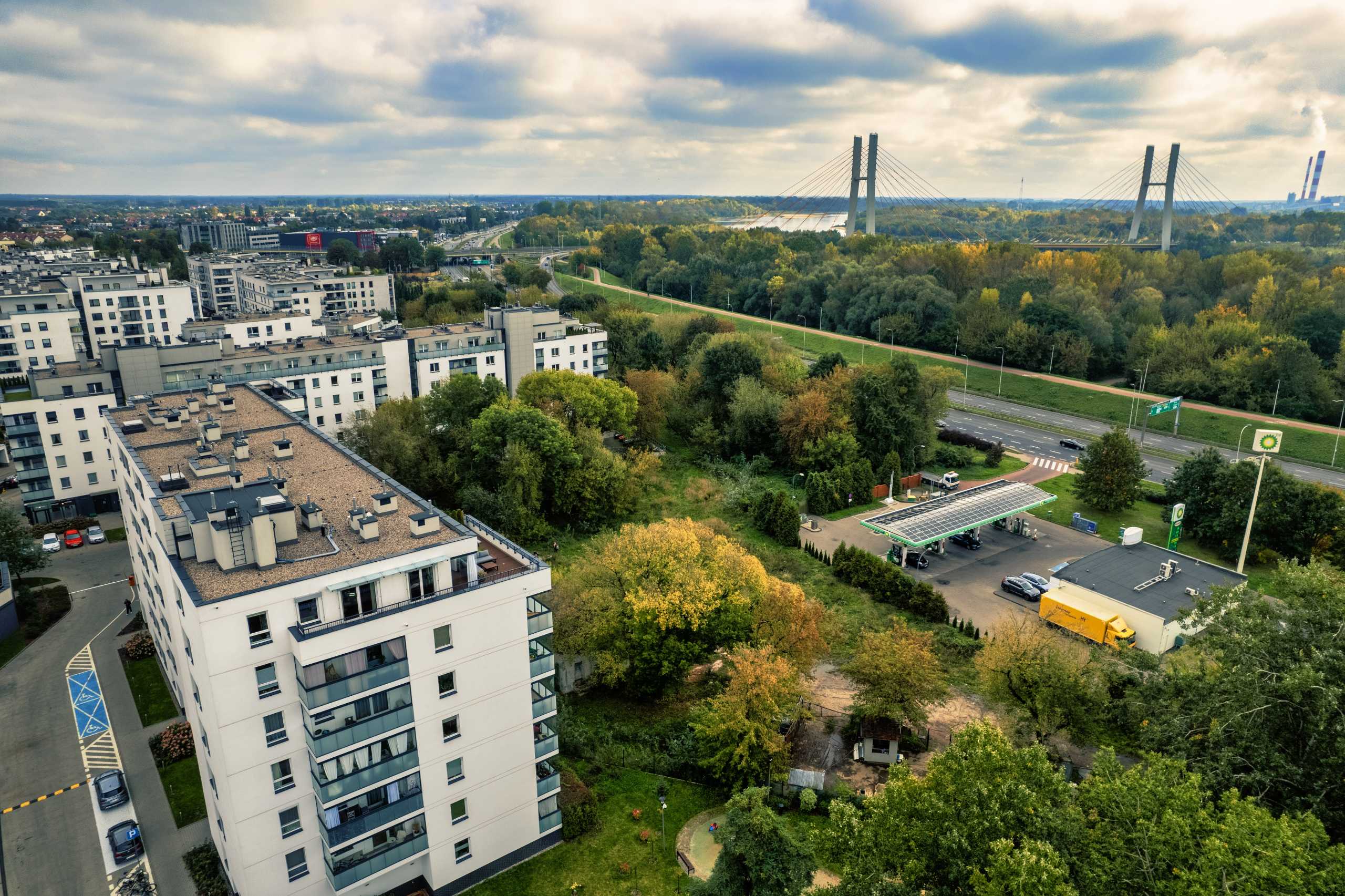 Widok z drona na okazały apartament w Warszawie oraz okoliczne tereny zielone i most.