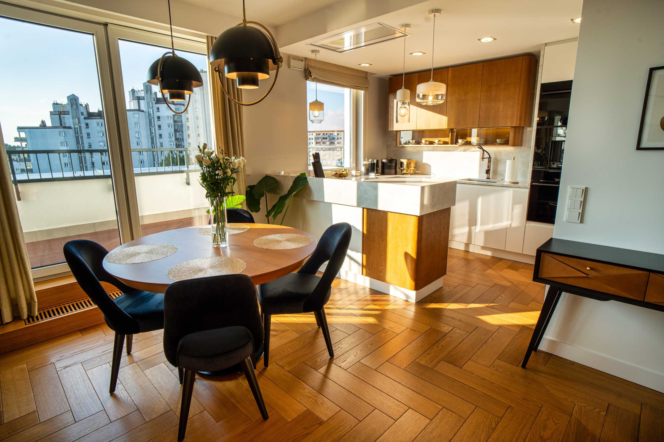 Fotografia wnętrz apartamentu w Warszawie — nowoczesna kuchnia z jadalnią i widokiem na miasto.
