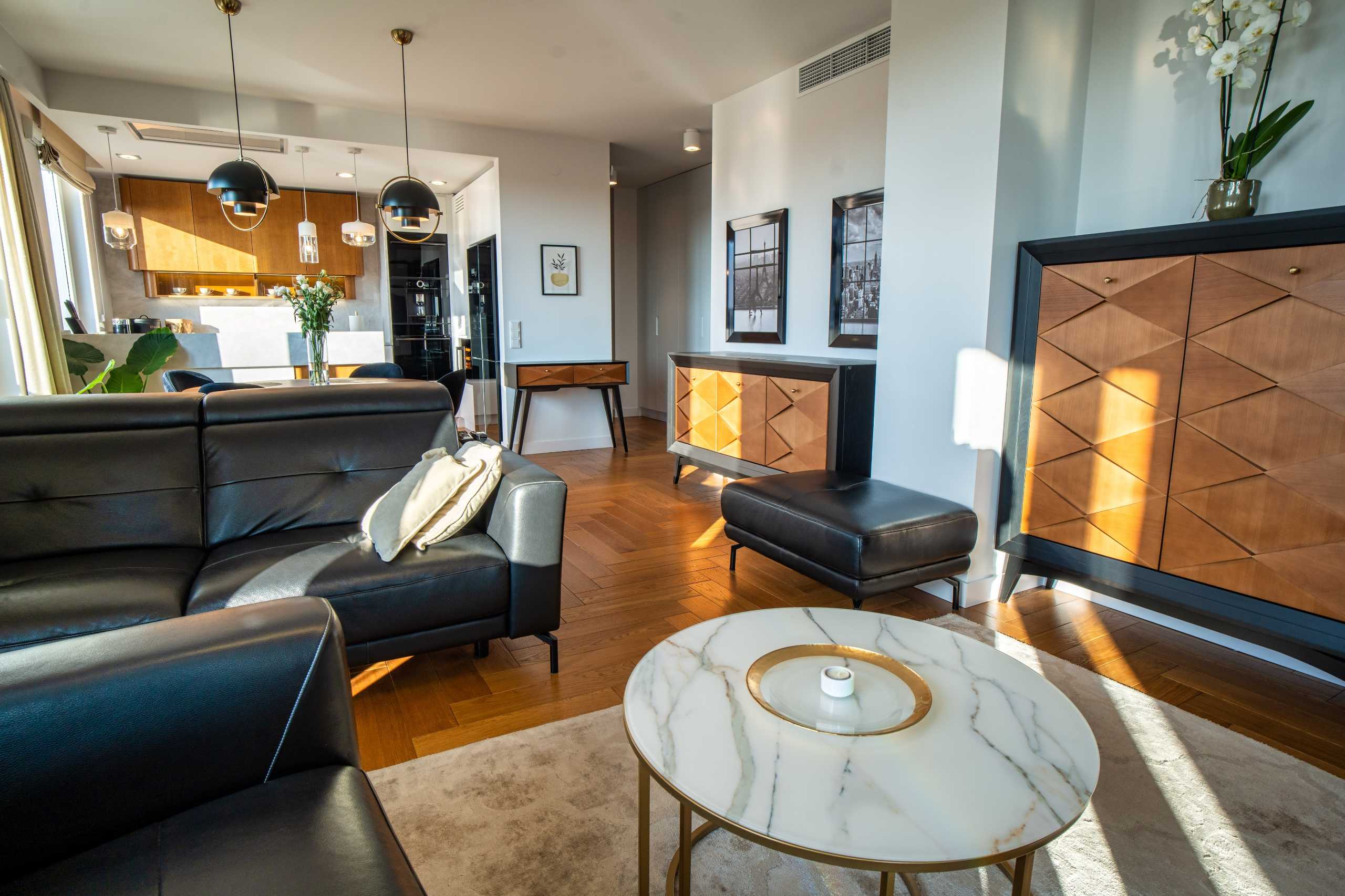 Eleganckie wnętrze apartamentu w Warszawie z nowoczesnym salonem, skórzanymi meblami i stylowym stolikiem.