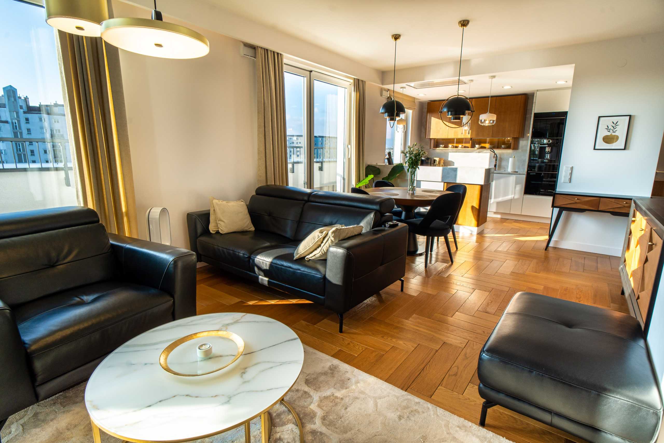 Stylowe wnętrze apartamentu w Warszawie z eleganckim salonem, sofami i nowoczesnym oświetleniem.