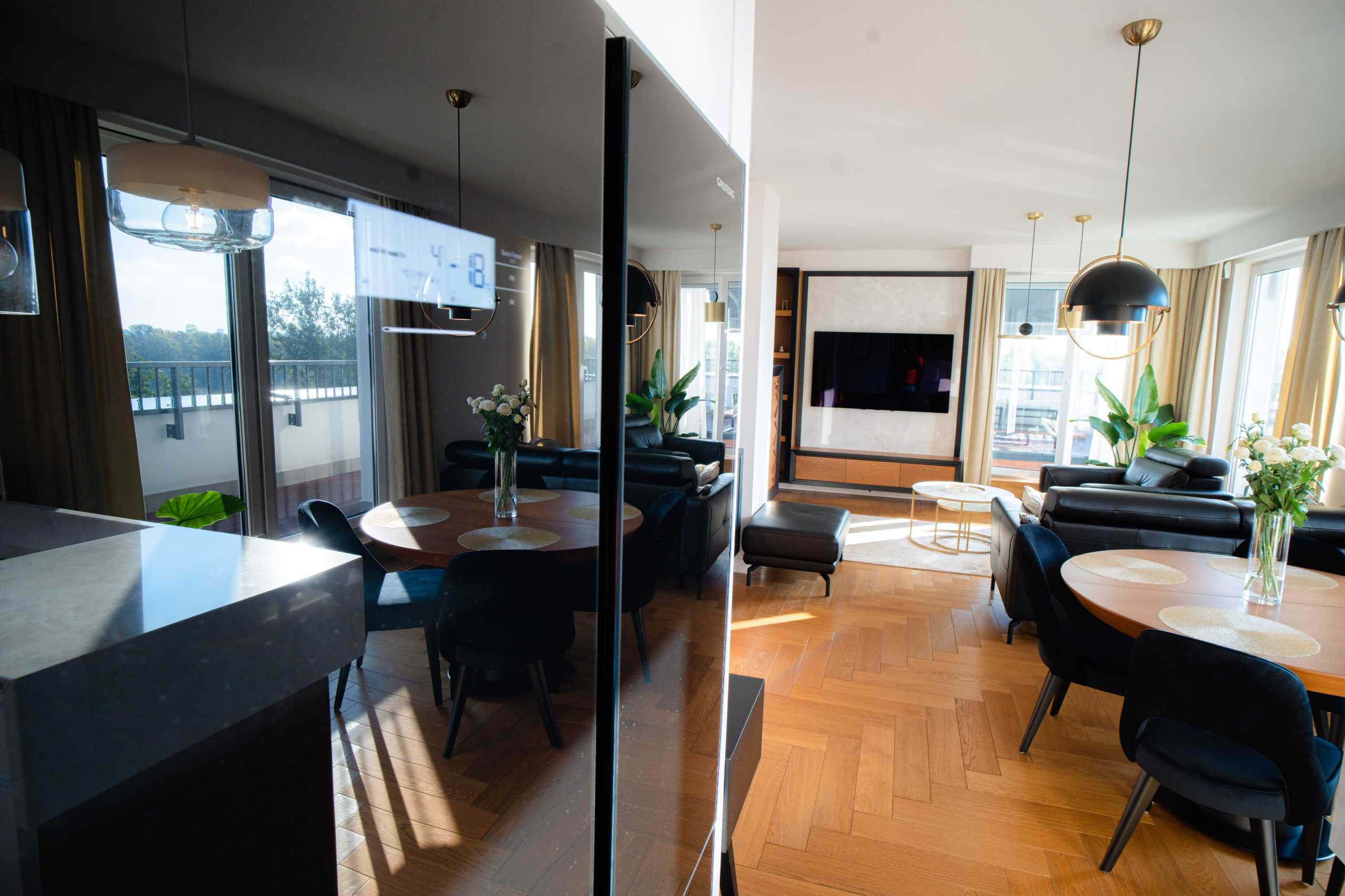 Fotografia wnętrz apartamentu w Warszawie — elegancka przestrzeń z salonem i jadalnią, z dużymi oknami i nowoczesnym wystrojem.