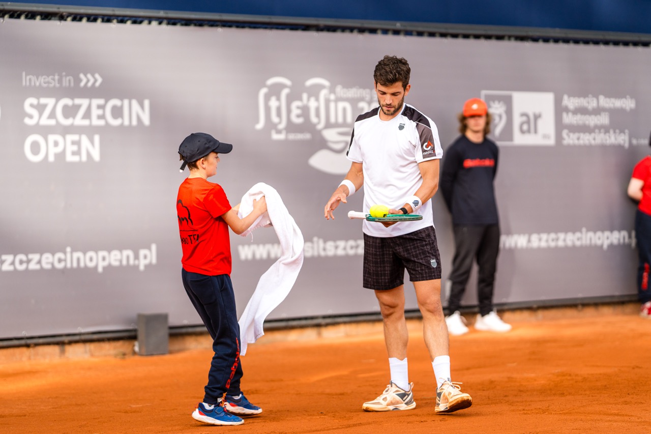 Zawodnik tenisa odbiera ręcznik od chłopca na korcie podczas turnieju Invest in Szczecin Open 2026.