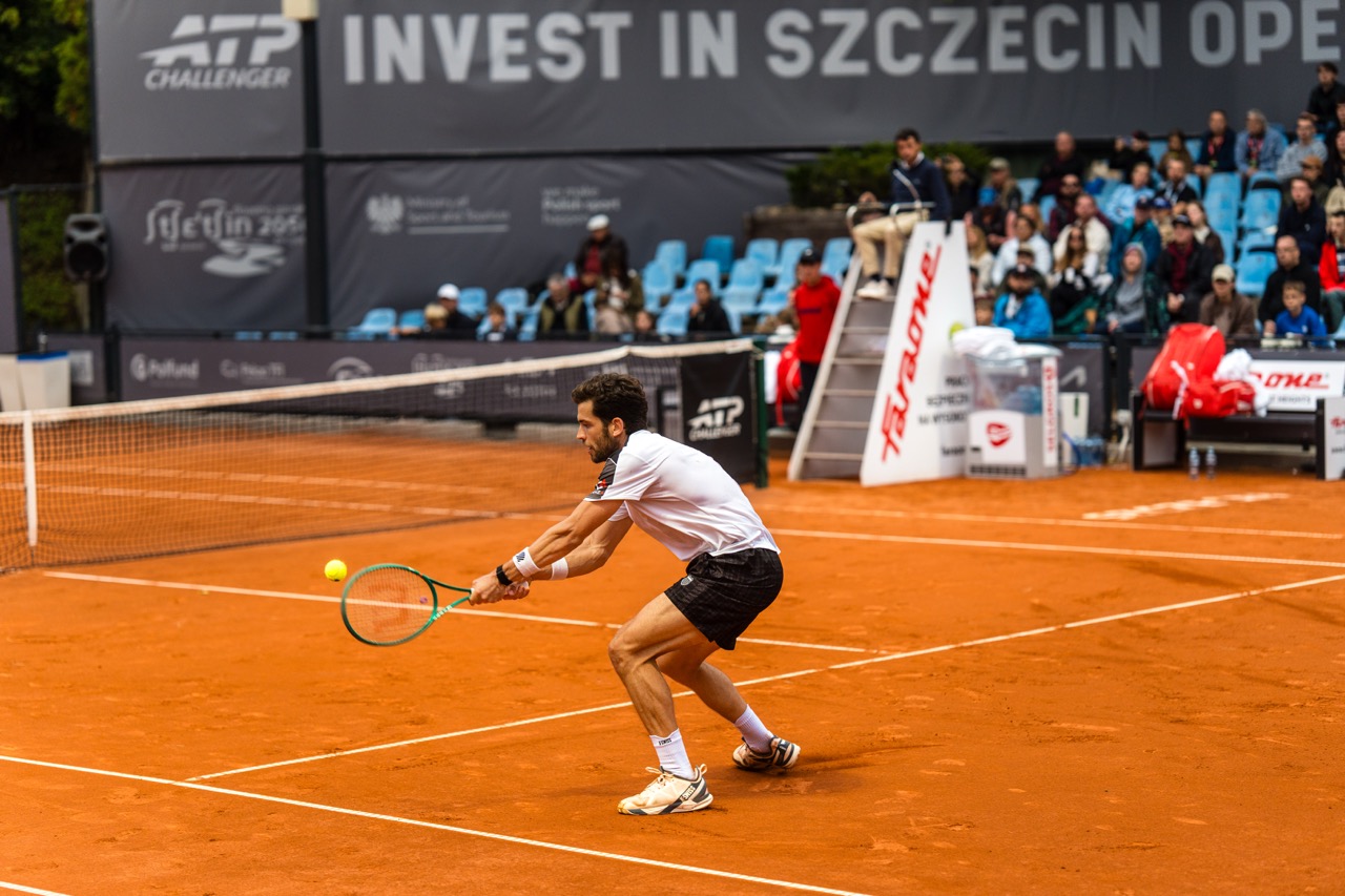 Zawodnik w trakcie dynamicznego serwisu podczas turnieju tenisa Invest in Szczecin Open 2026 na korcie ziemnym.