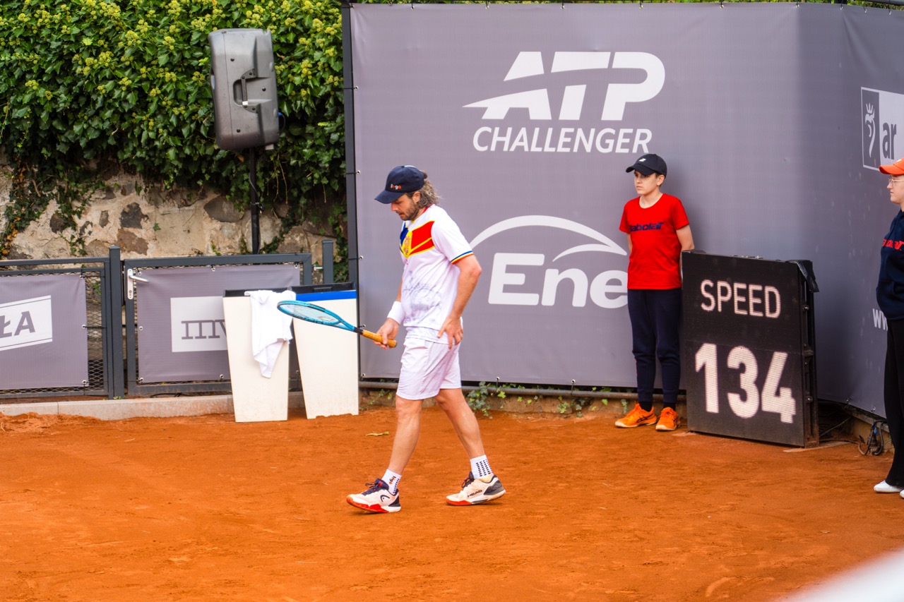 Zawodnik tenisa na korcie podczas turnieju Invest in Szczecin Open 2026, z tablicą prędkości w tle.