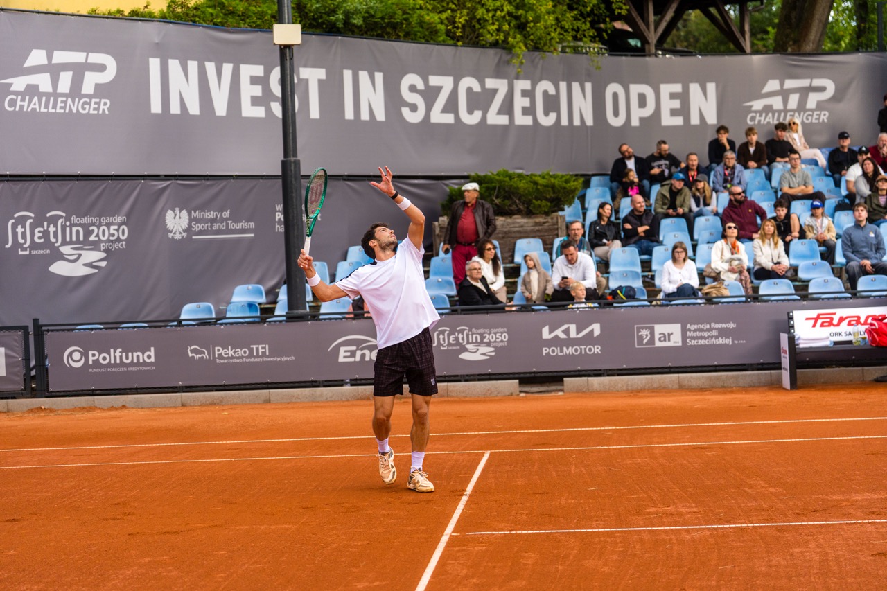 Zawodnik w białej koszulce serwuje piłkę podczas turnieju tenisa Invest in Szczecin Open 2026.