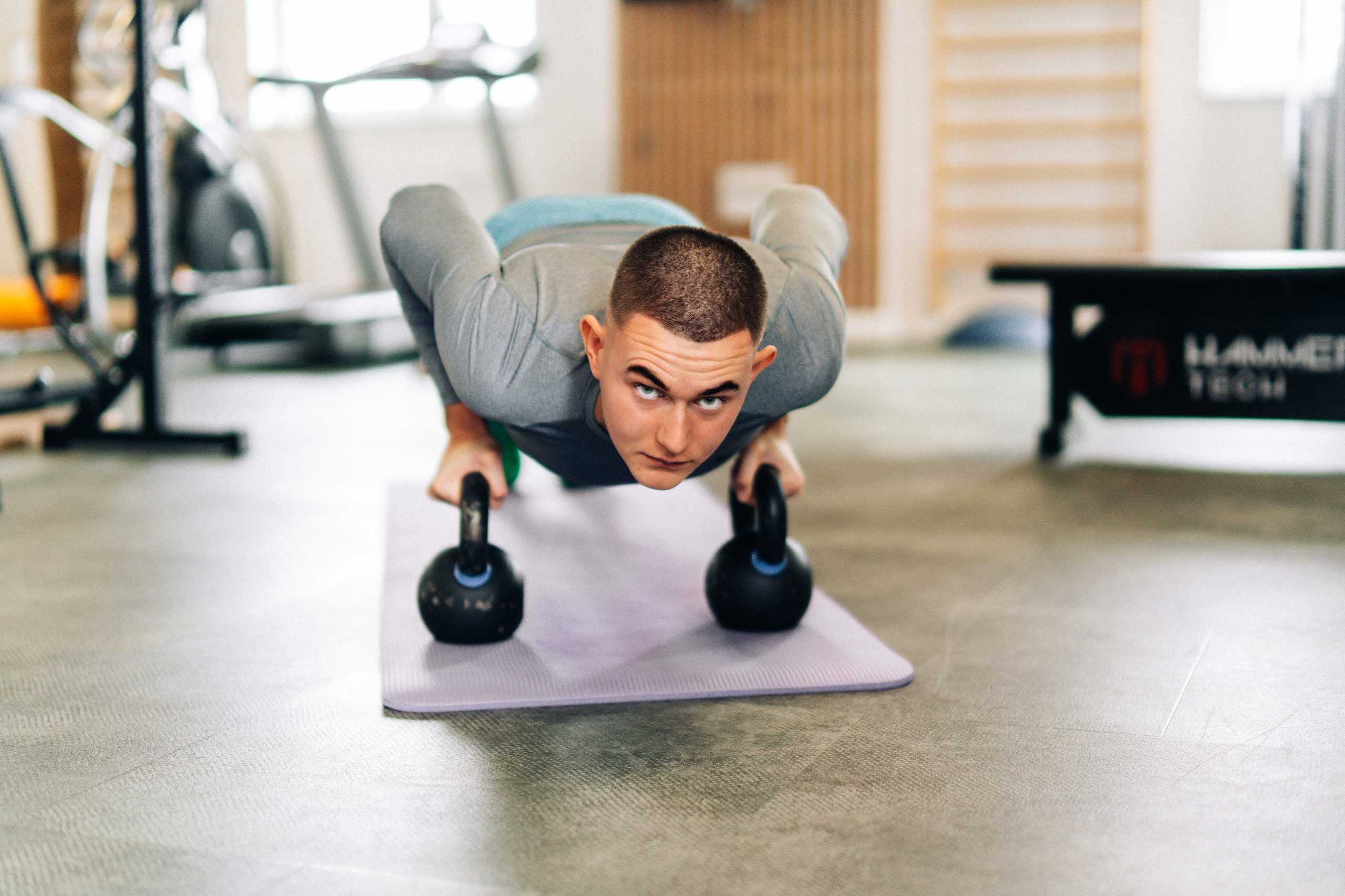 Trener wykonujący ćwiczenie z kettlebellami w Klubie Fitnes 3L w Mierzynie, podkreślający zaangażowanie w trening.