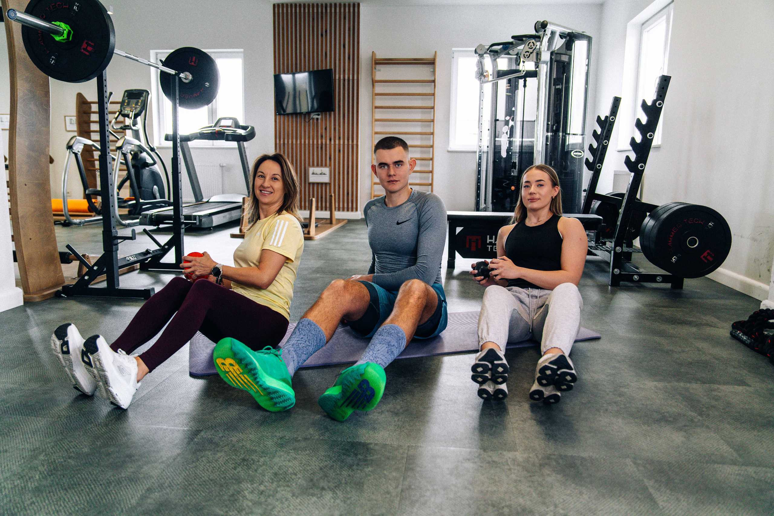 Trenerzy w akcji w Klubie Fitnes 3L w Mierzynie, prezentujący różnorodne ćwiczenia na macie.