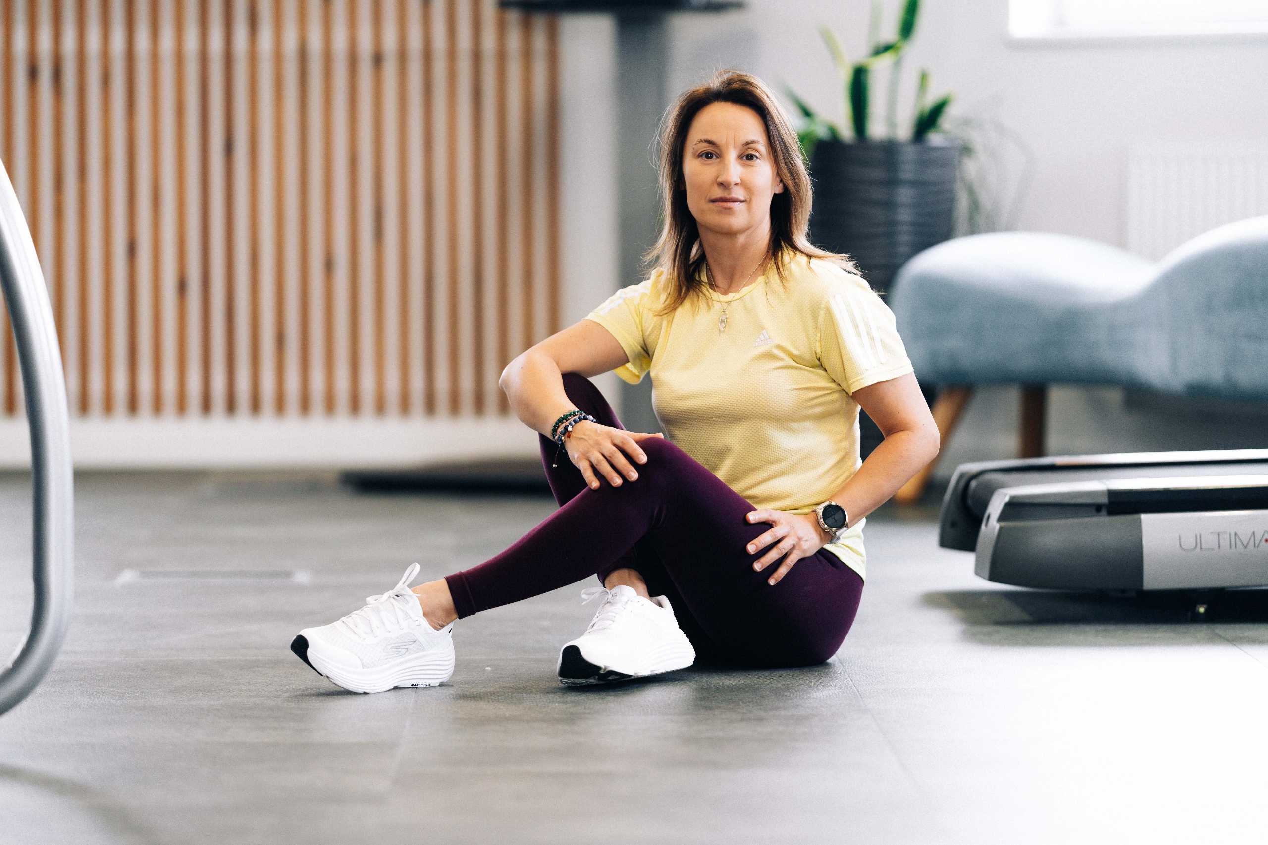 Trenerka w żółtej koszulce i fioletowych legginsach w klubie fitness 3L w Mierzynie, prezentująca ćwiczenia na podłodze.