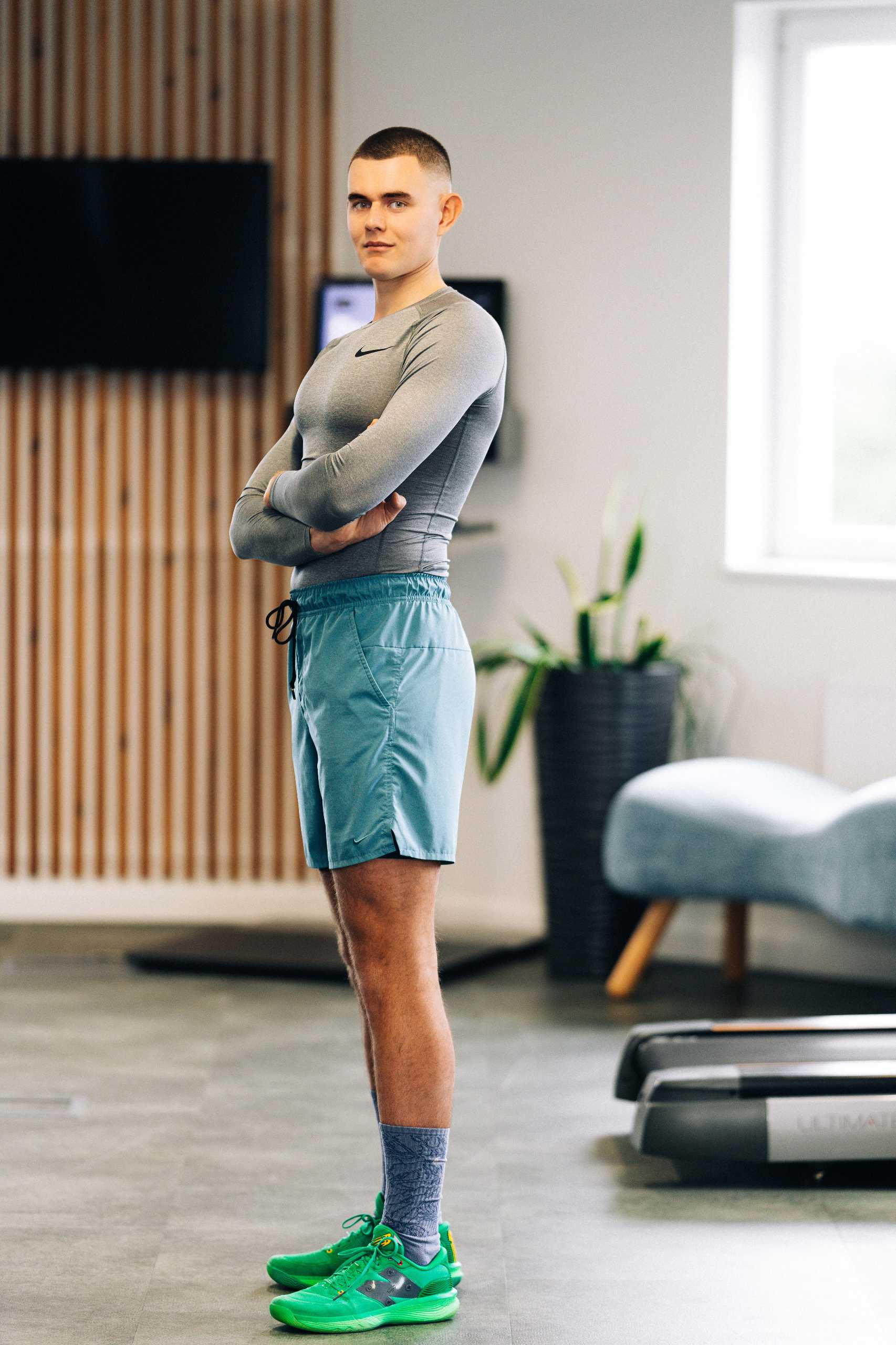 Trener w klubie fitness 3L w Mierzynie, ubrany w sportowy strój, z pewnością stoi z założonymi rękami.
