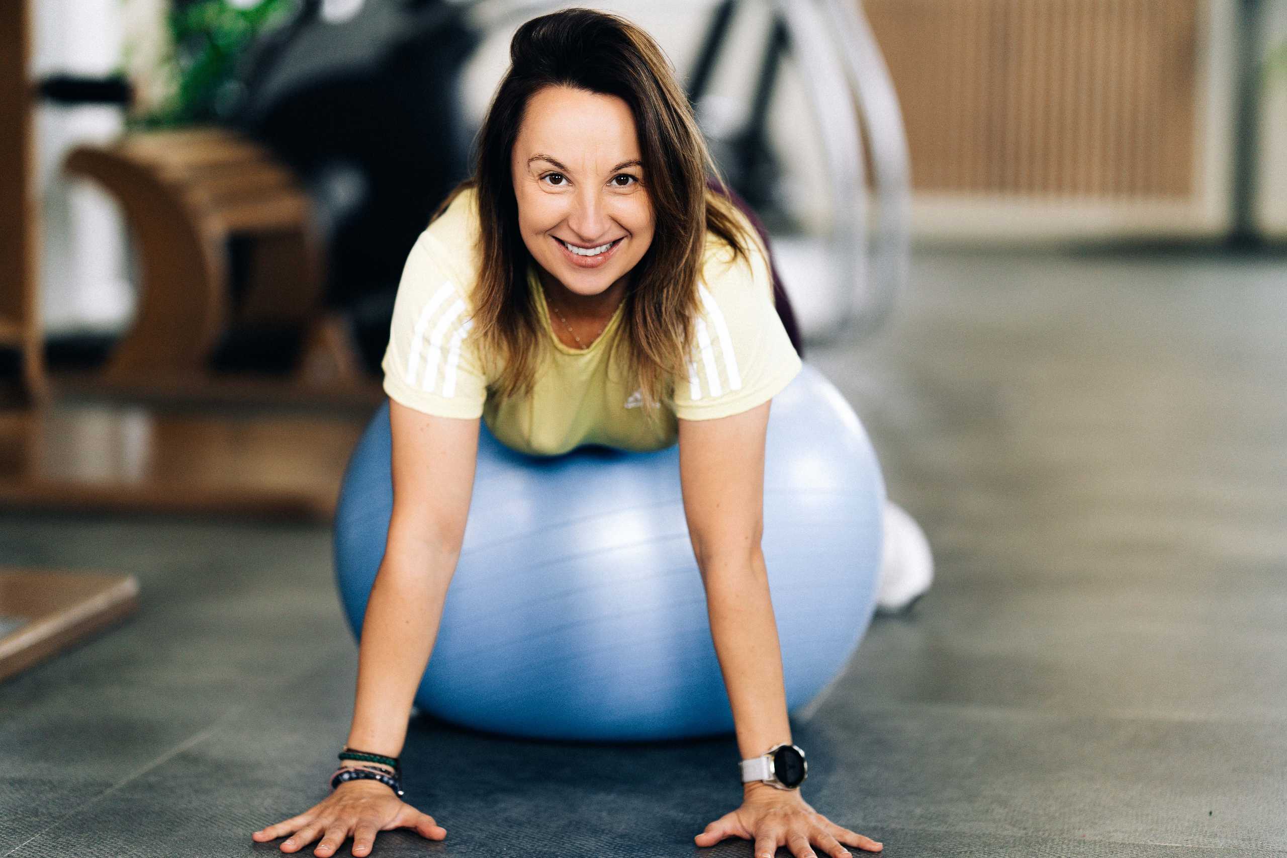 Trenerka na piłce do ćwiczeń w Klubie Fitnes 3L w Mierzynie, uśmiechnięta i zaangażowana w trening.