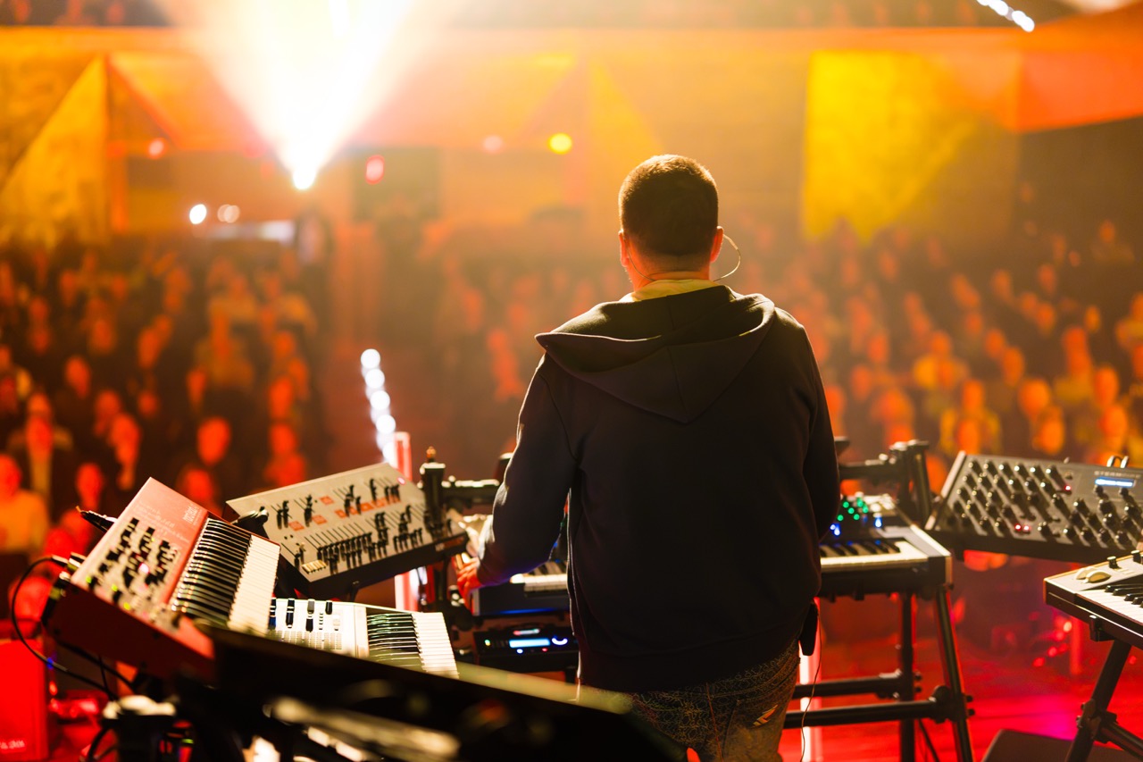 Fotografia koncertowa z perspektywy muzyka w Filharmonii Szczecińskiej, z widownią w tle i efektownym oświetleniem.