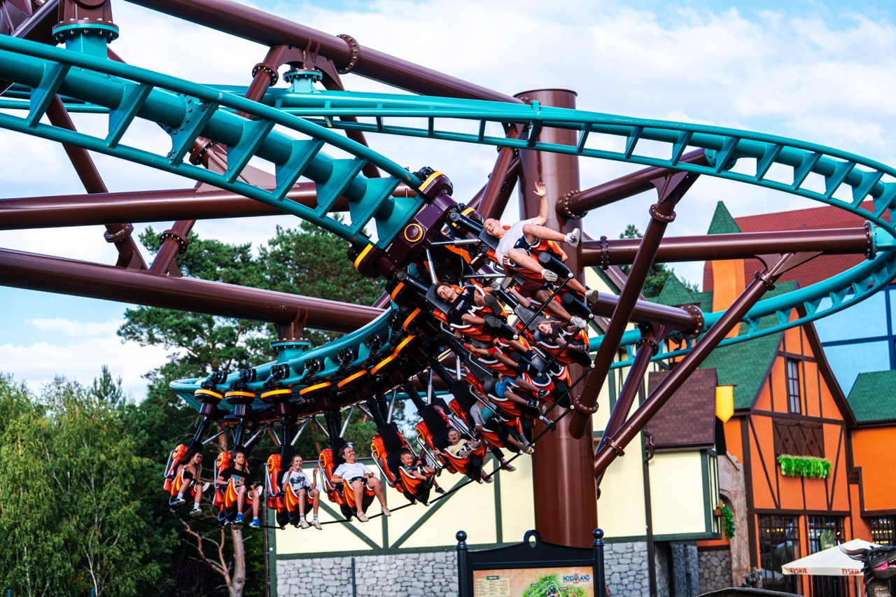 Ujęcie z drona w Hossolandzie — roller coaster w akcji, w tle kolorowe budynki parku rozrywki.