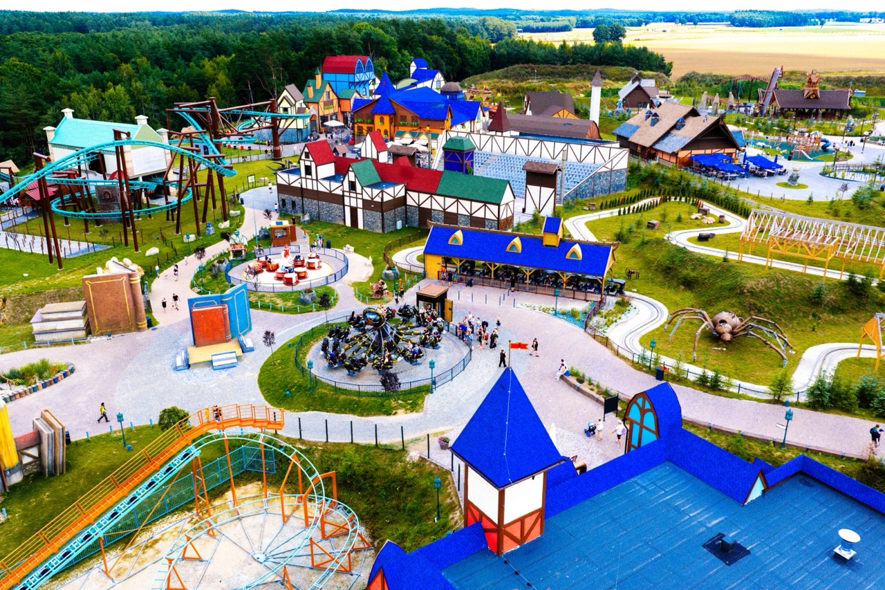 Fotografia z drona przedstawiająca park rozrywki Hossoland na Pomorzu — kolorowe atrakcje i goście w ruchu.