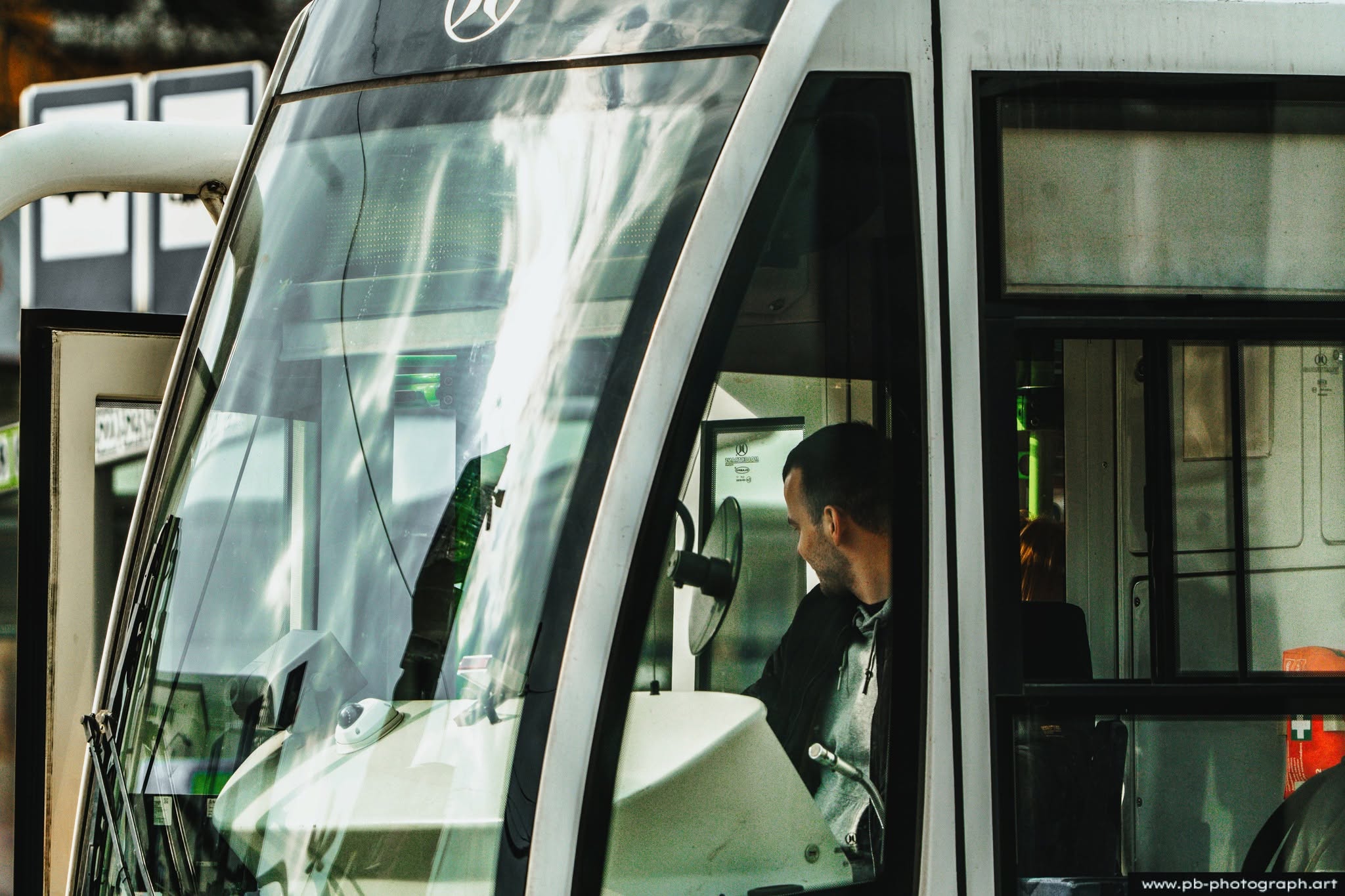 Fotografia uliczna Szczecin — kierowca autobusu w kabinie, uchwycony z bliska przez teleobiektyw.