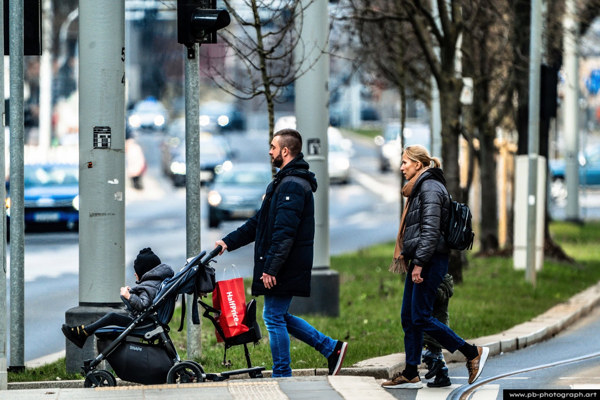 Rodzina przechodzi przez ulicę w Szczecinie, mężczyzna prowadzi wózek dziecięcy, a kobieta idzie obok.
