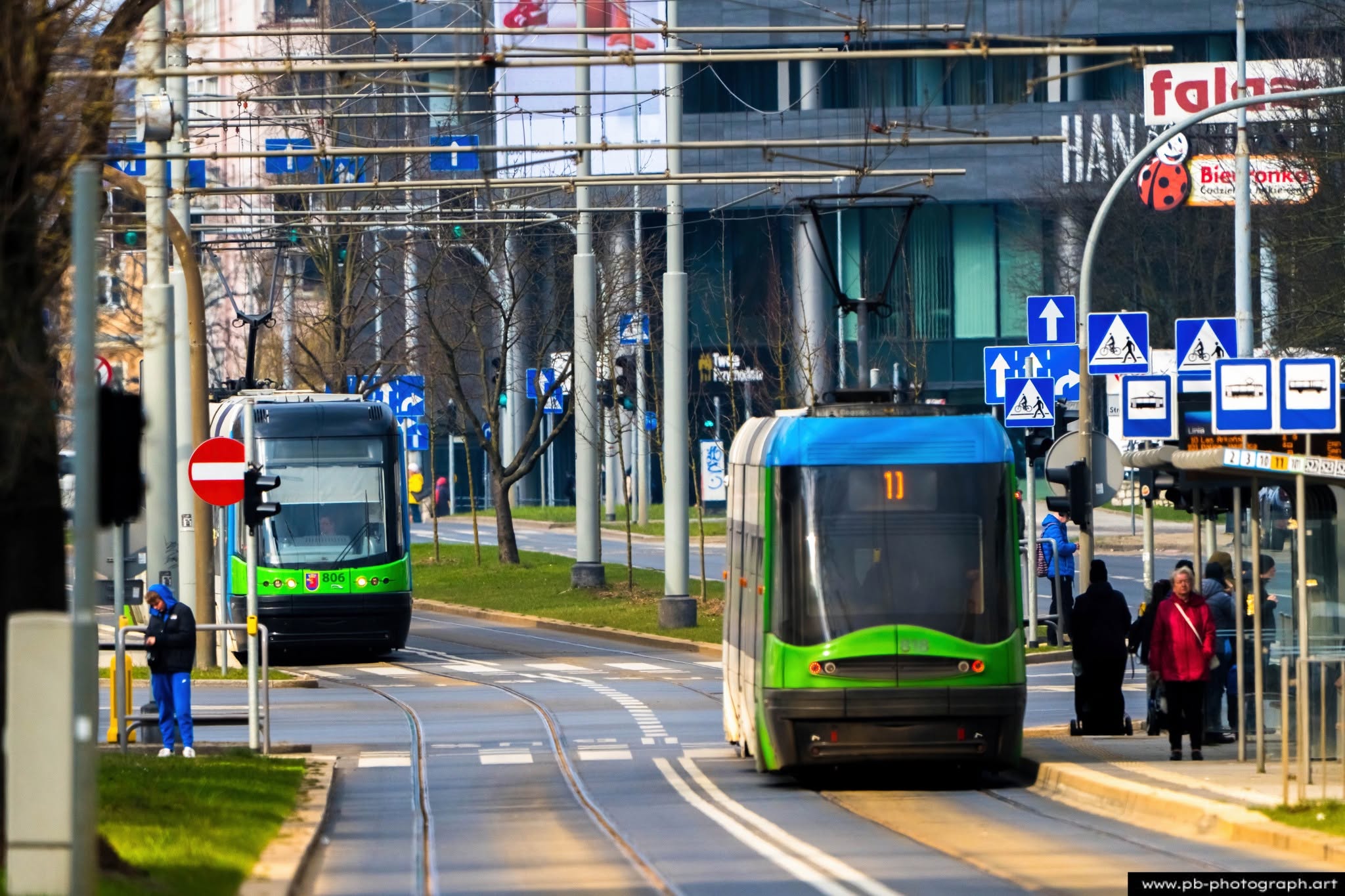 Fotografia uliczna w Szczecinie — tramwaje na przystanku, z pasażerami oczekującymi na transport.