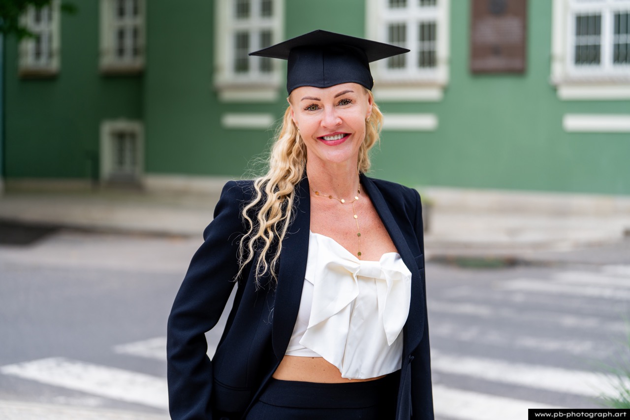 Uczestniczka absolutorium w Szczecinie z dyplomem na tle Urzędu Miasta.