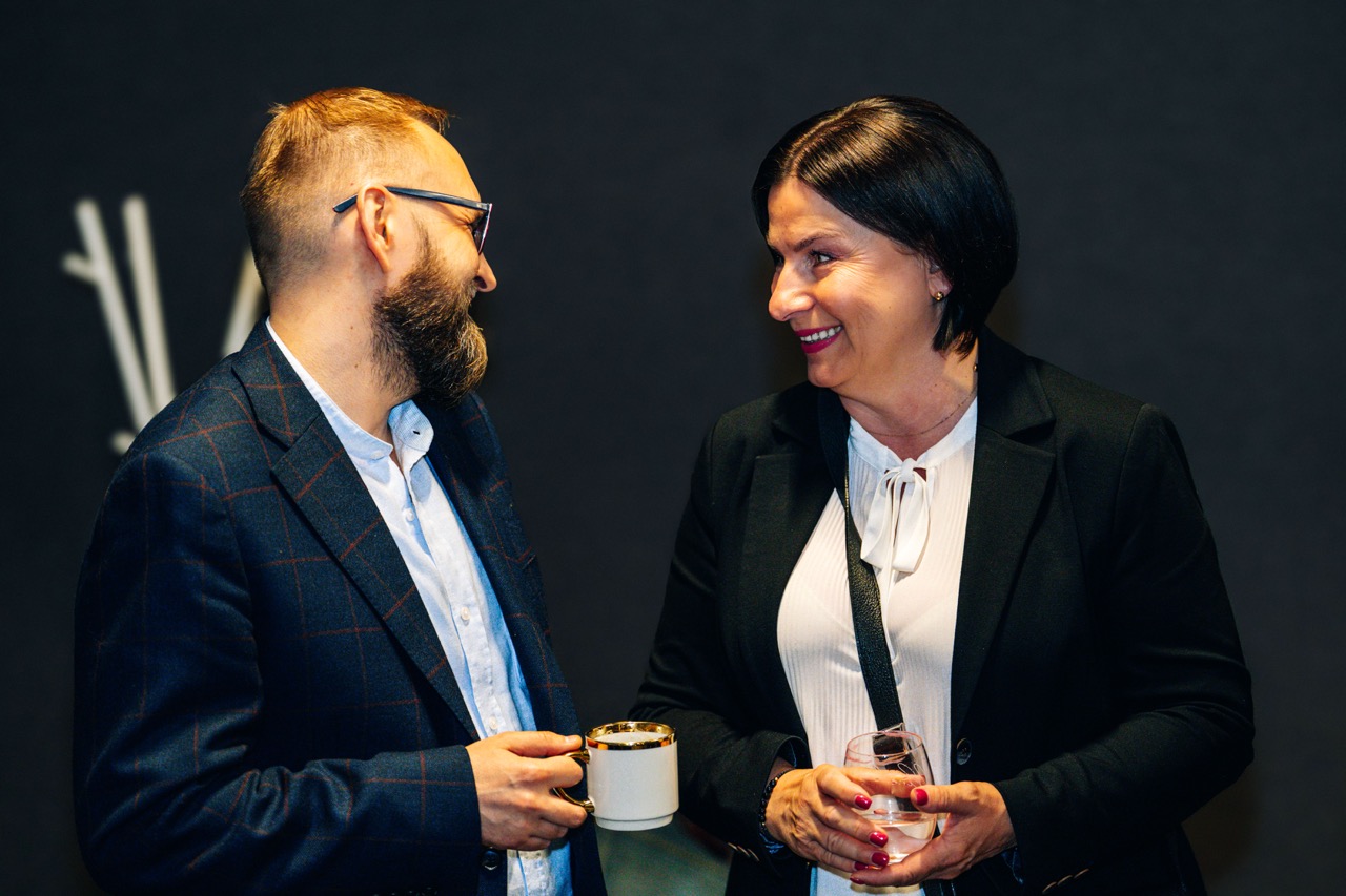 Dwoje uczestników wydarzenia rozmawia w piwnicy hotelu Fokus, otoczeni ciemnymi ścianami.