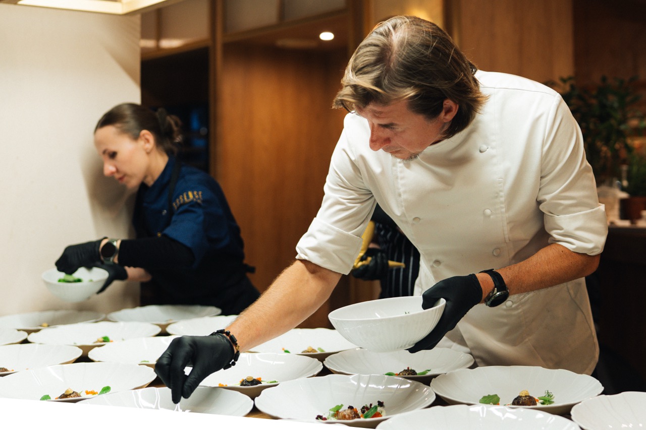 Fotografia korporacyjna Karola Okrasy w Szczecinie — przygotowanie potraw w eleganckim wnętrzu restauracji.
