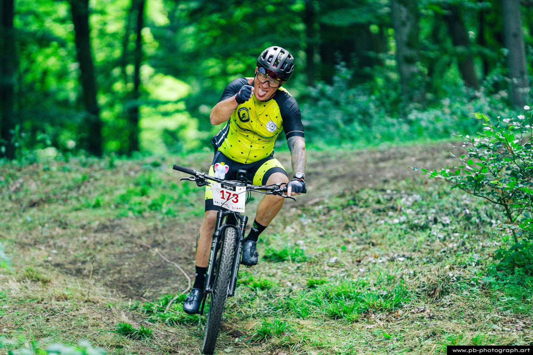 Fotografia sportowa z wyścigów MTB w Szczecinie — zawodnik na trasie z uśmiechem i radością z jazdy.
