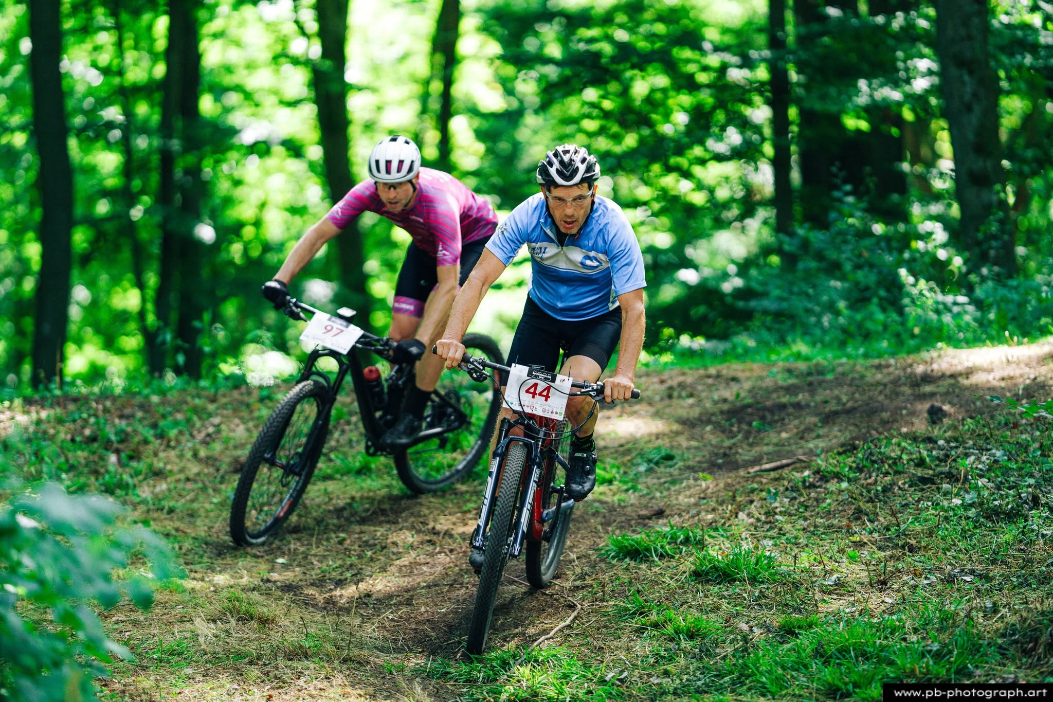 Fotografia sportowa z wyścigów MTB w Szczecinie — zawodnicy na trasie wśród zieleni.