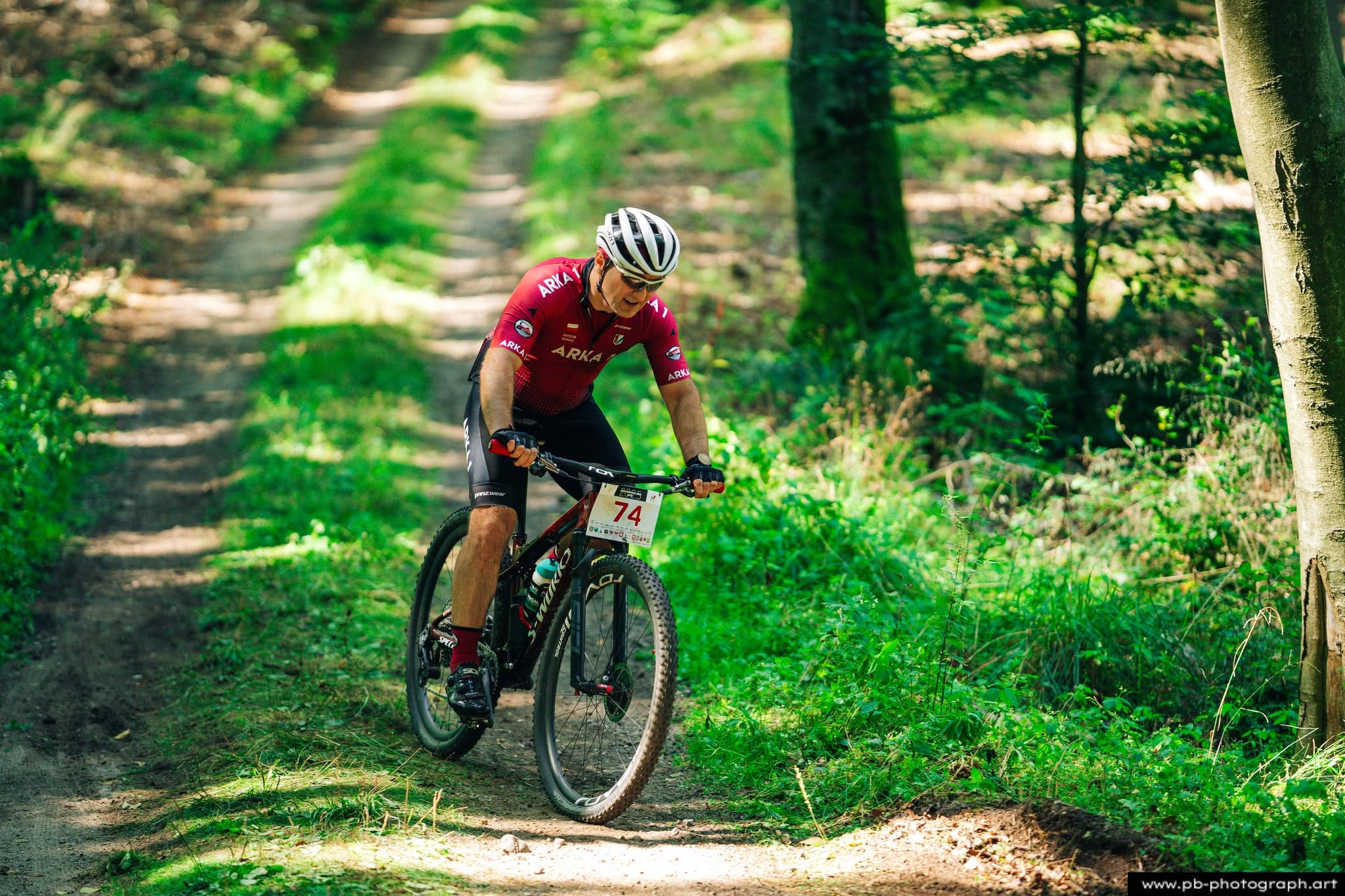 Fotografia sportowa z wyścigów MTB w Szczecinie — zawodnik pokonujący trasę w lesie.