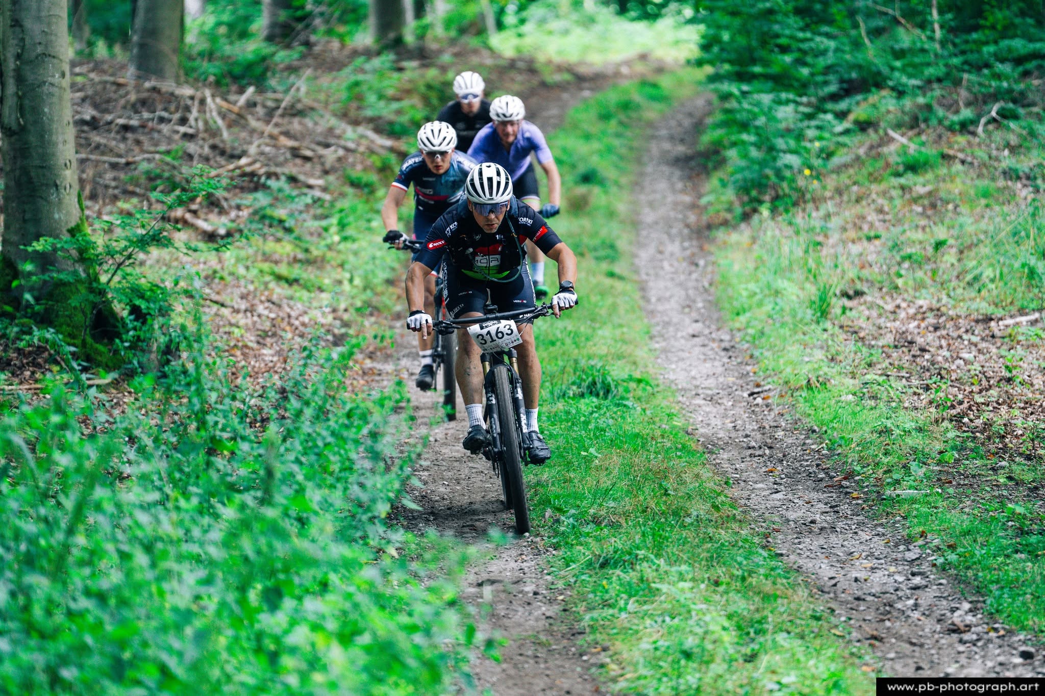 Fotografia sportowa z wyścigów MTB w Szczecinie — zawodnicy na trasie w lesie.