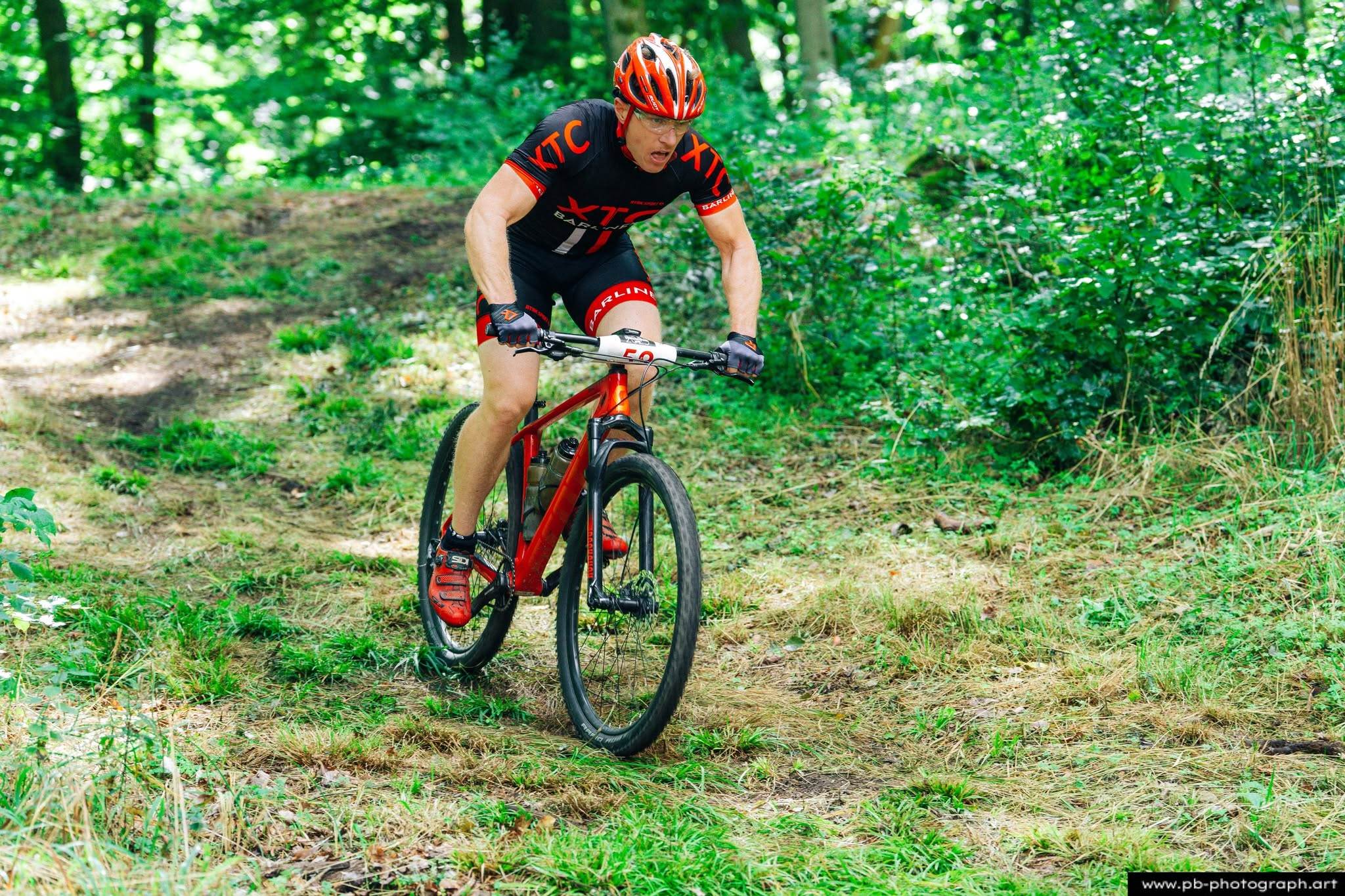 Fotografia sportowa z wyścigów MTB w Szczecinie — zawodnik pokonujący trasę w lesie.