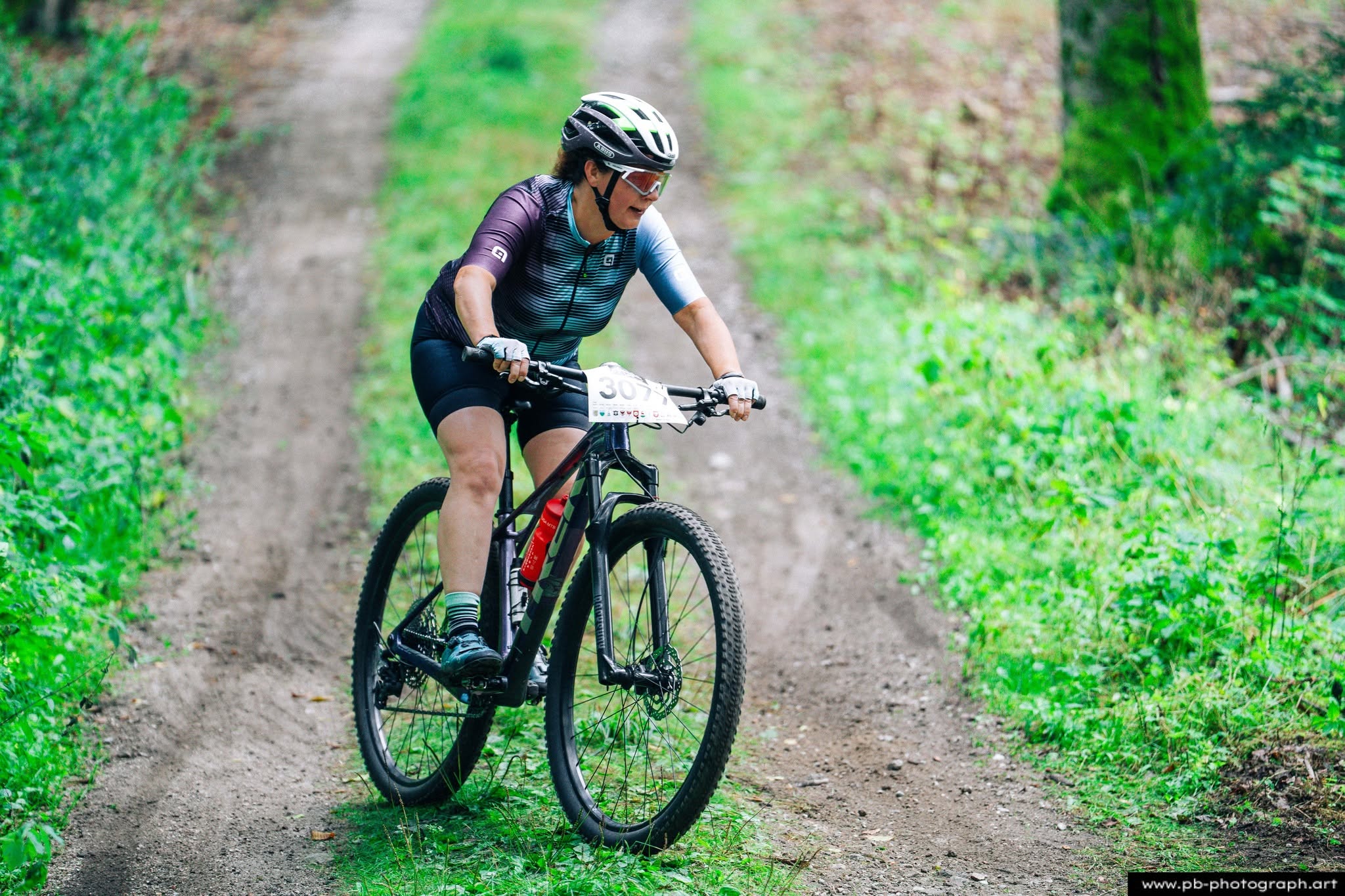 Zawodniczka na trasie wyścigu MTB w Szczecinie, dynamiczna rywalizacja w otoczeniu natury.
