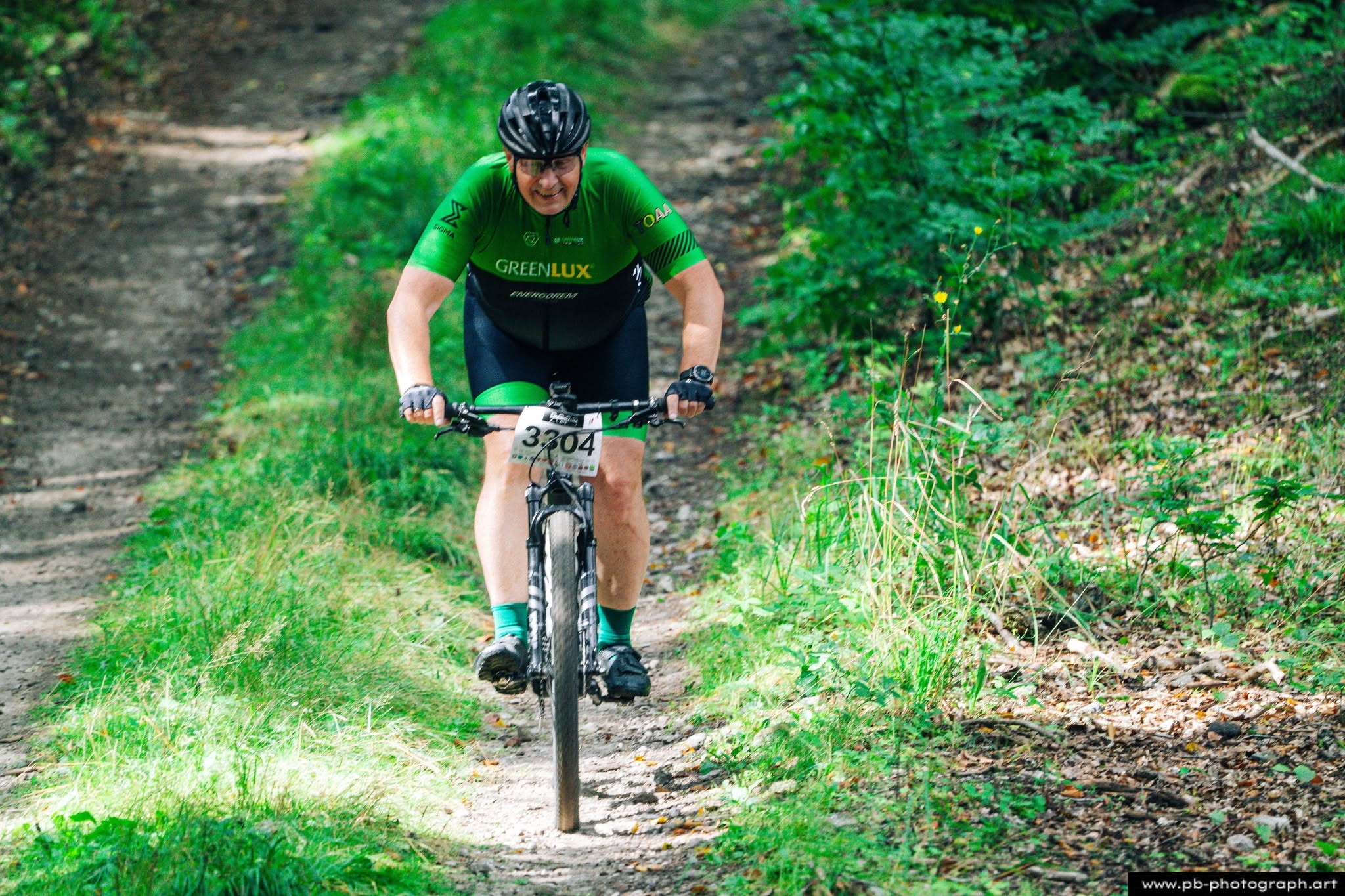 Fotografia sportowa z wyścigów MTB w Szczecinie — zawodnik pokonujący trasę w lesie.