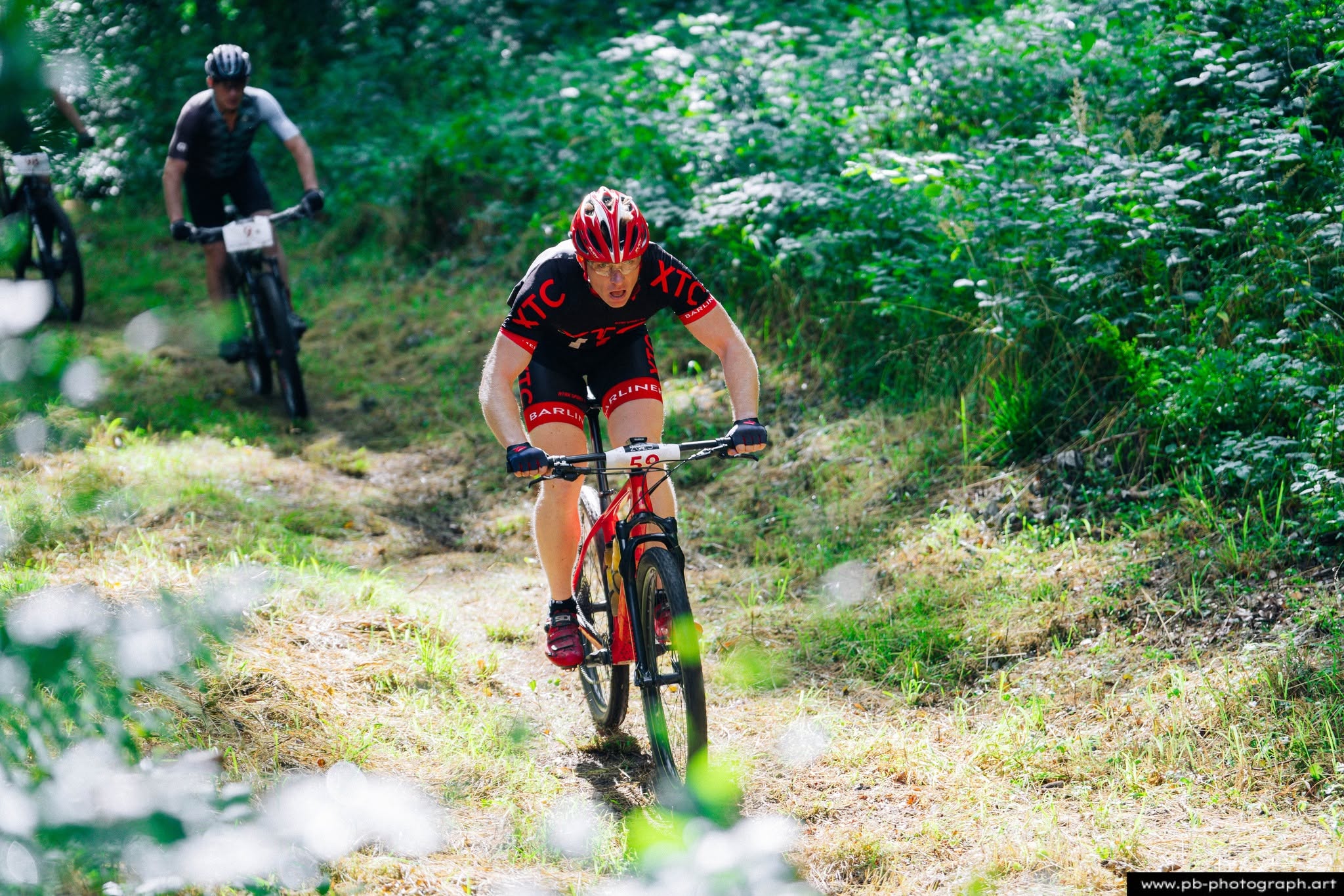 Fotografia sportowa z wyścigów MTB w Szczecinie — zawodnik pokonujący trasę w lesie.