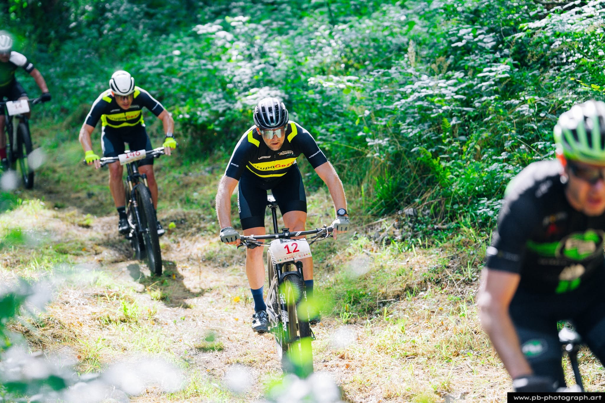 Fotografia sportowa z wyścigów MTB w Szczecinie — zawodnicy na trasie w lesie.