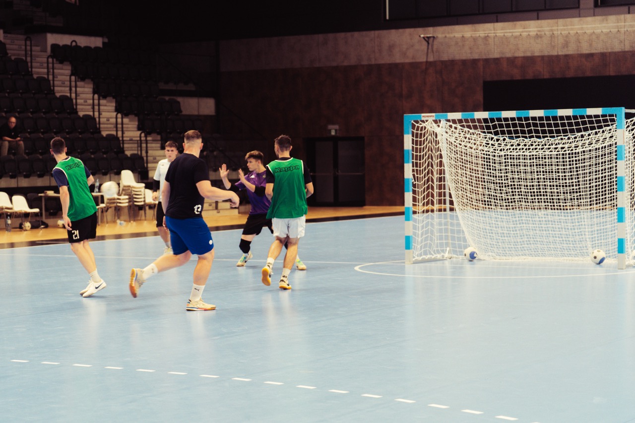 Dynamiczne ujęcie z treningu Szczecińskiej Akademii Futsalu — zawodnicy w akcji na boisku w Hali SDS.