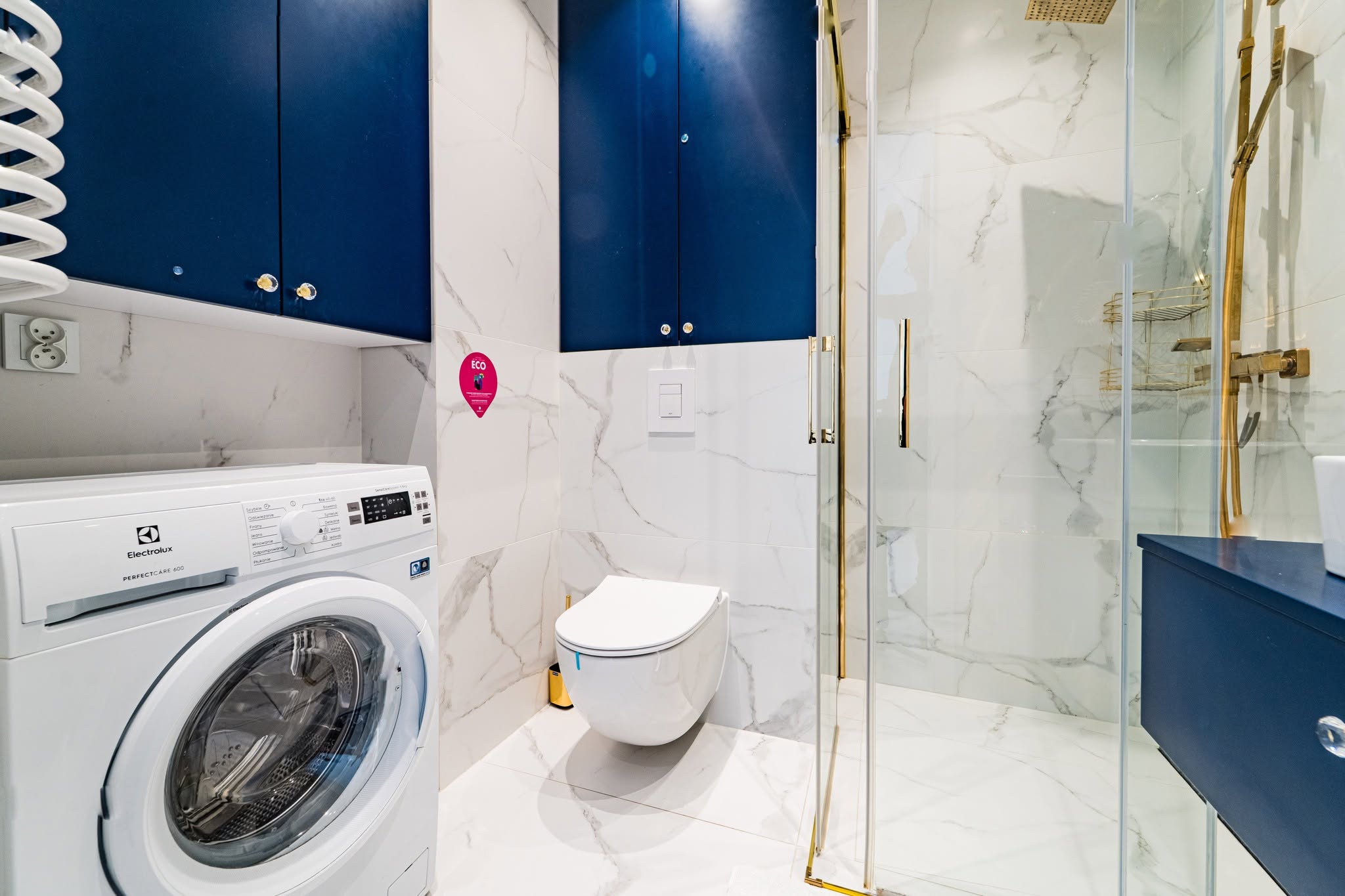 Fotografia wnętrz nowoczesnej łazienki w apartamencie w Mielnie z prysznicem i pralką.