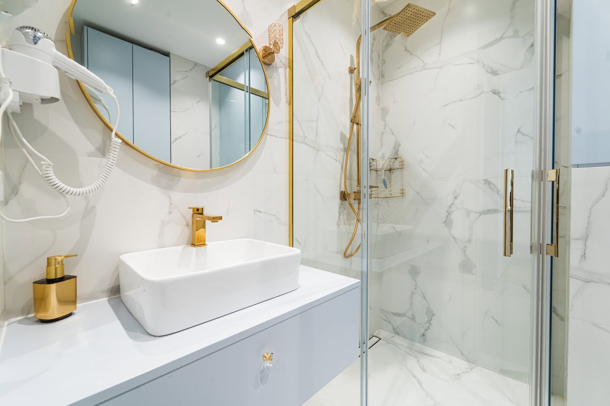Elegancka łazienka w apartamencie z minimalistycznym umywalką i złotymi akcentami w Mielnie.
