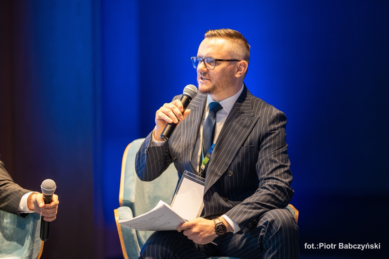 Prelegent podczas konferencji BusinessContact6 w Szczecinie, trzyma mikrofon i prowadzi dyskusję.