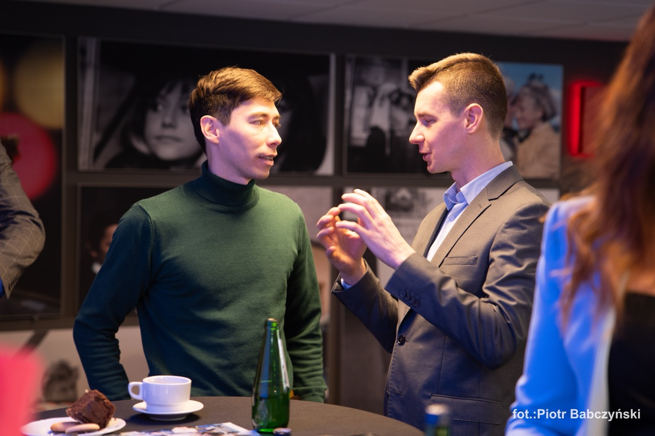 Dwóch mężczyzn rozmawia przy okrągłym stoliku podczas wydarzenia BusinessContact6 w Szczecinie.